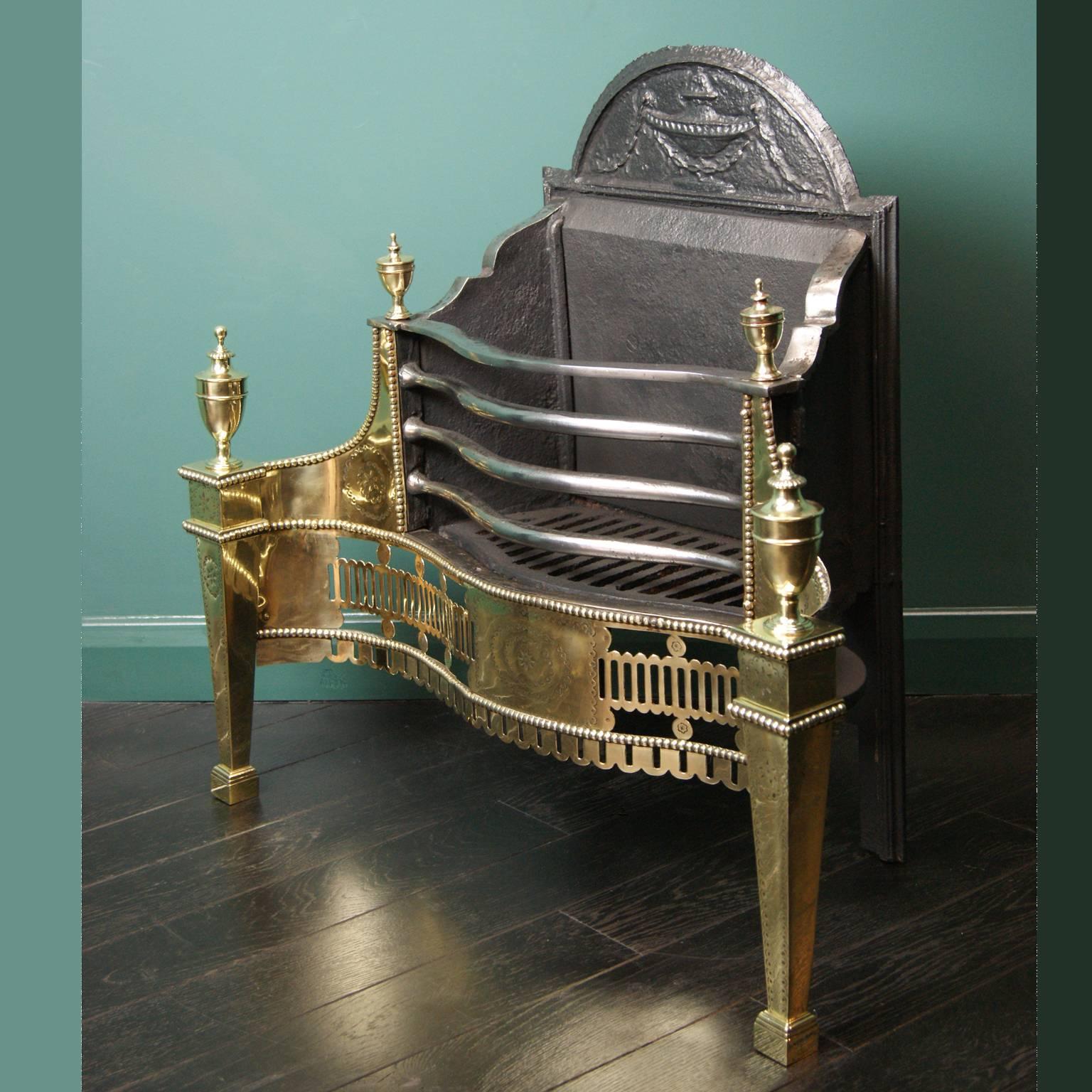 An English polished brass and wrought iron fire grate (by Thomas Elsley.) The detailed fluted fret is set between square tapered legs with large brass urns. Fine engraving on wings, legs and fret. wrought iron fire bars and original backplate.