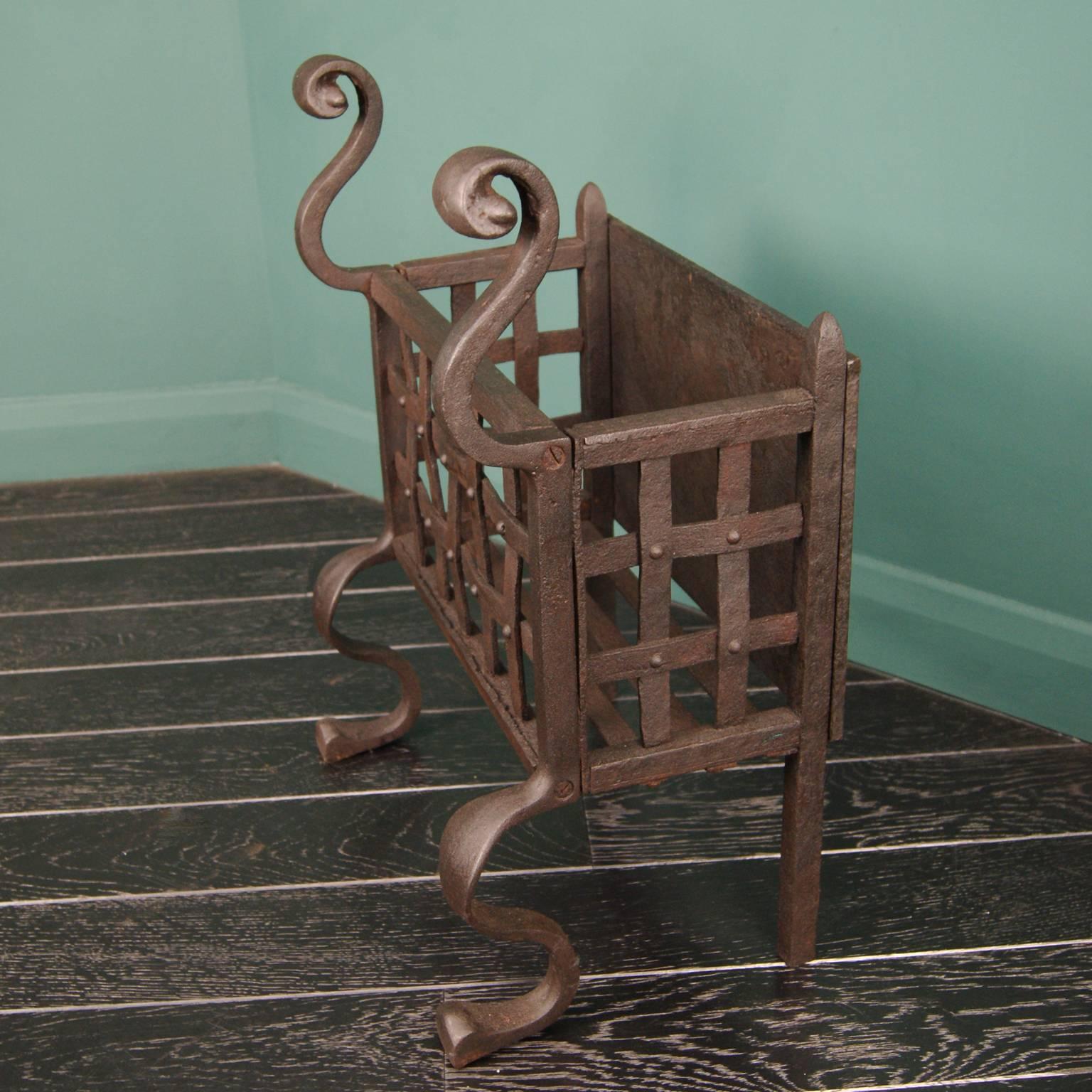 A small elegant wrought and cast iron fire basket, with rivet-work detail, scroll finials and shaped legs.