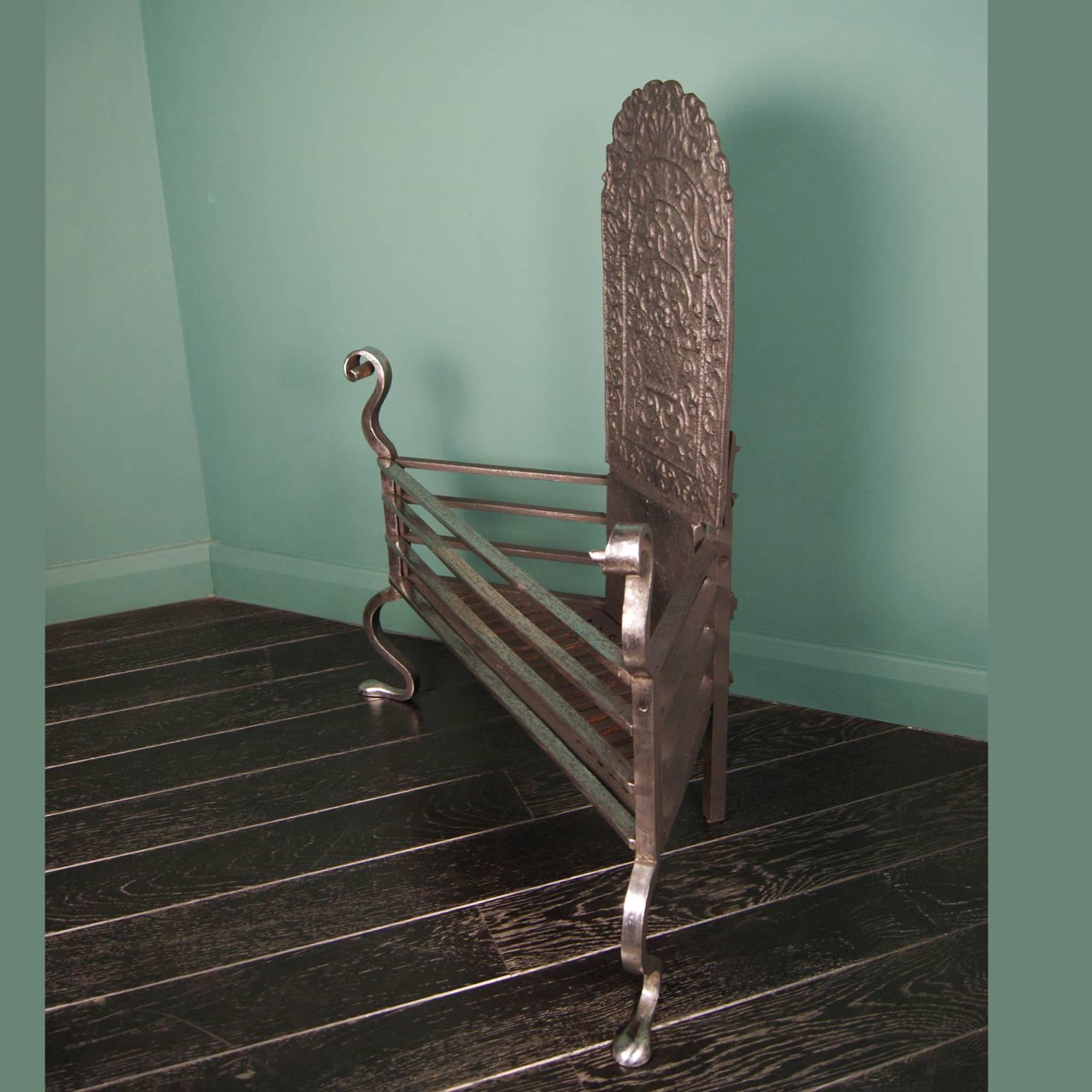 A polished 19th century wrought-iron corner grate by Thomas Elsley, with scroll finials, shaped feet and decorative fire back, circa 1890.

Width at rear 25.5cm 10".
