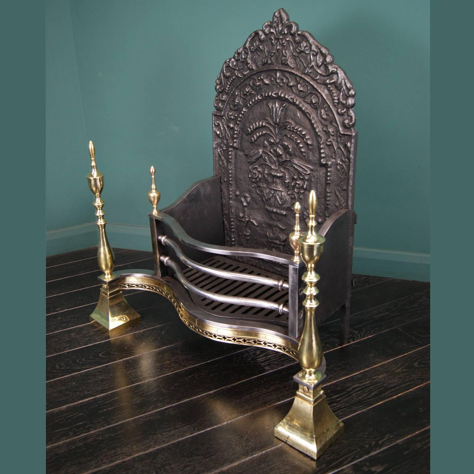 A late 19th century brass and steel dog fireplace, grate with polished steel fire bars, slim openwork brass fret and brass standards with tall urn finials. The shaped ornate fire back with vase and foliage detailing. Restored. 

