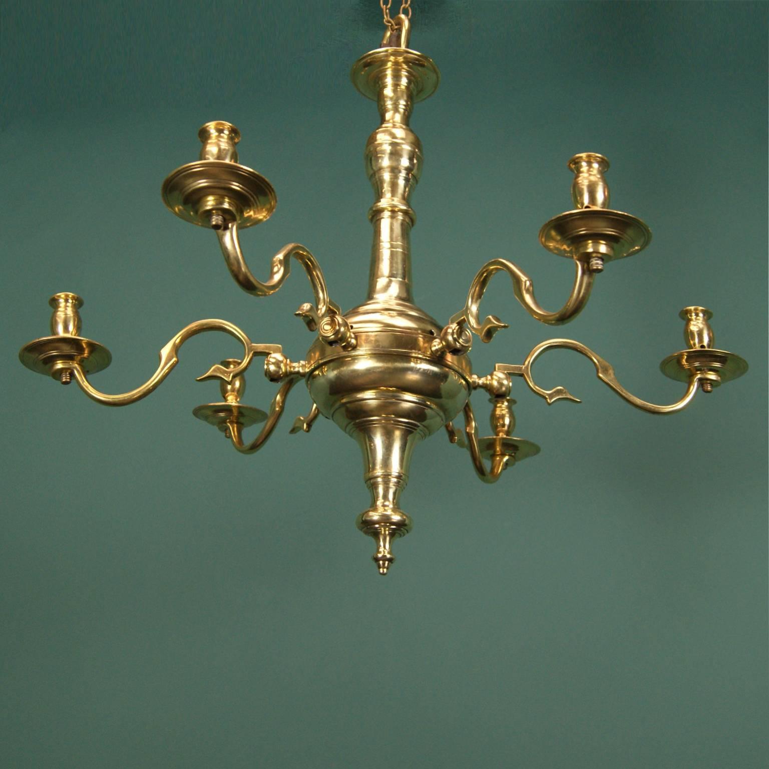 An elegant English six-branch brass chandelier. The collared ring detail on the central sphere holds the branches; each s-scroll arm is individually marked and housed in mortised joint flanges extending from the central ring.  All central elements