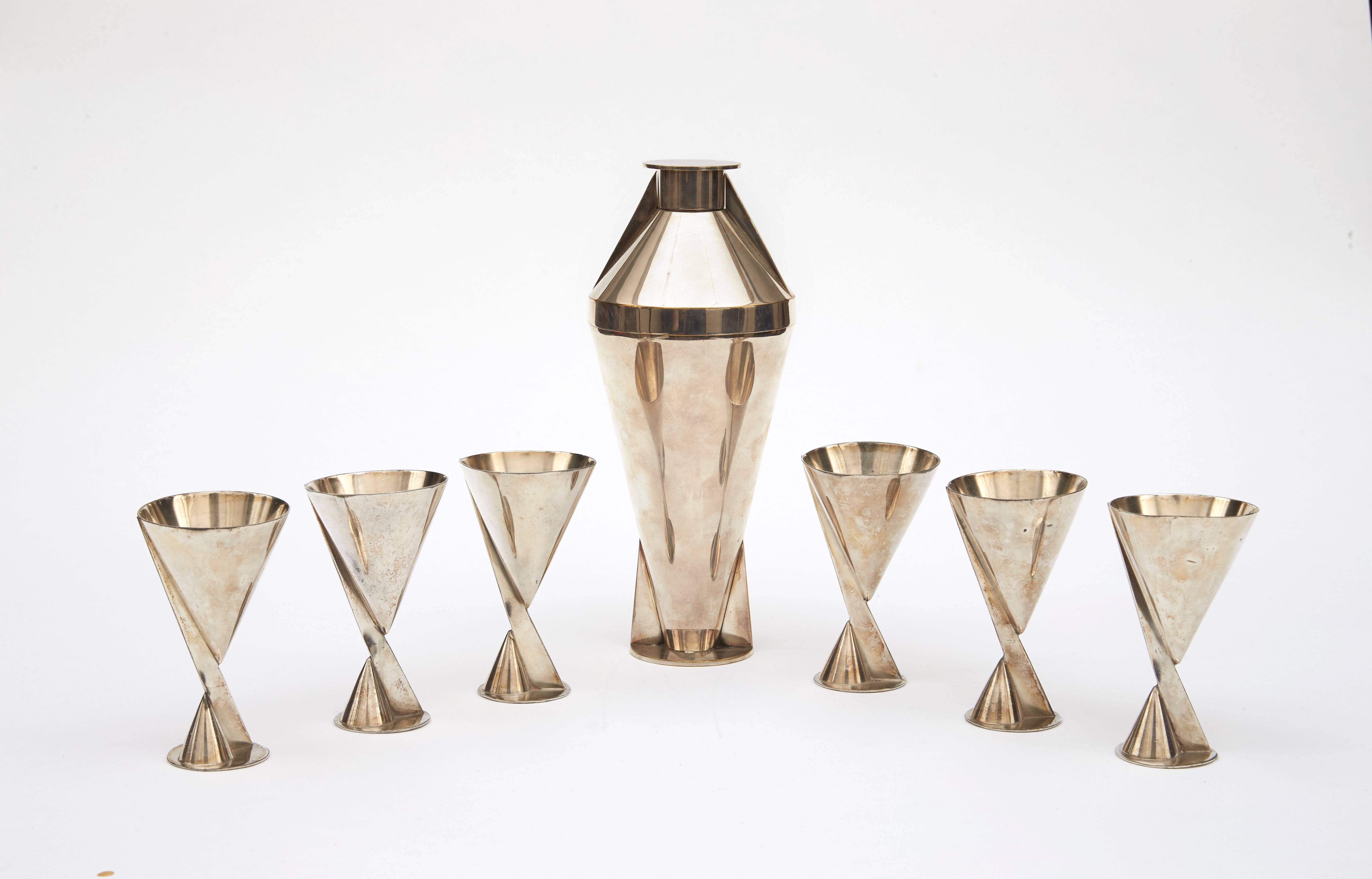 Cocktail set composed with a tapered silver-plated metal shaker and six cocktail glasses in silver-plated metal. Underside stamped with 