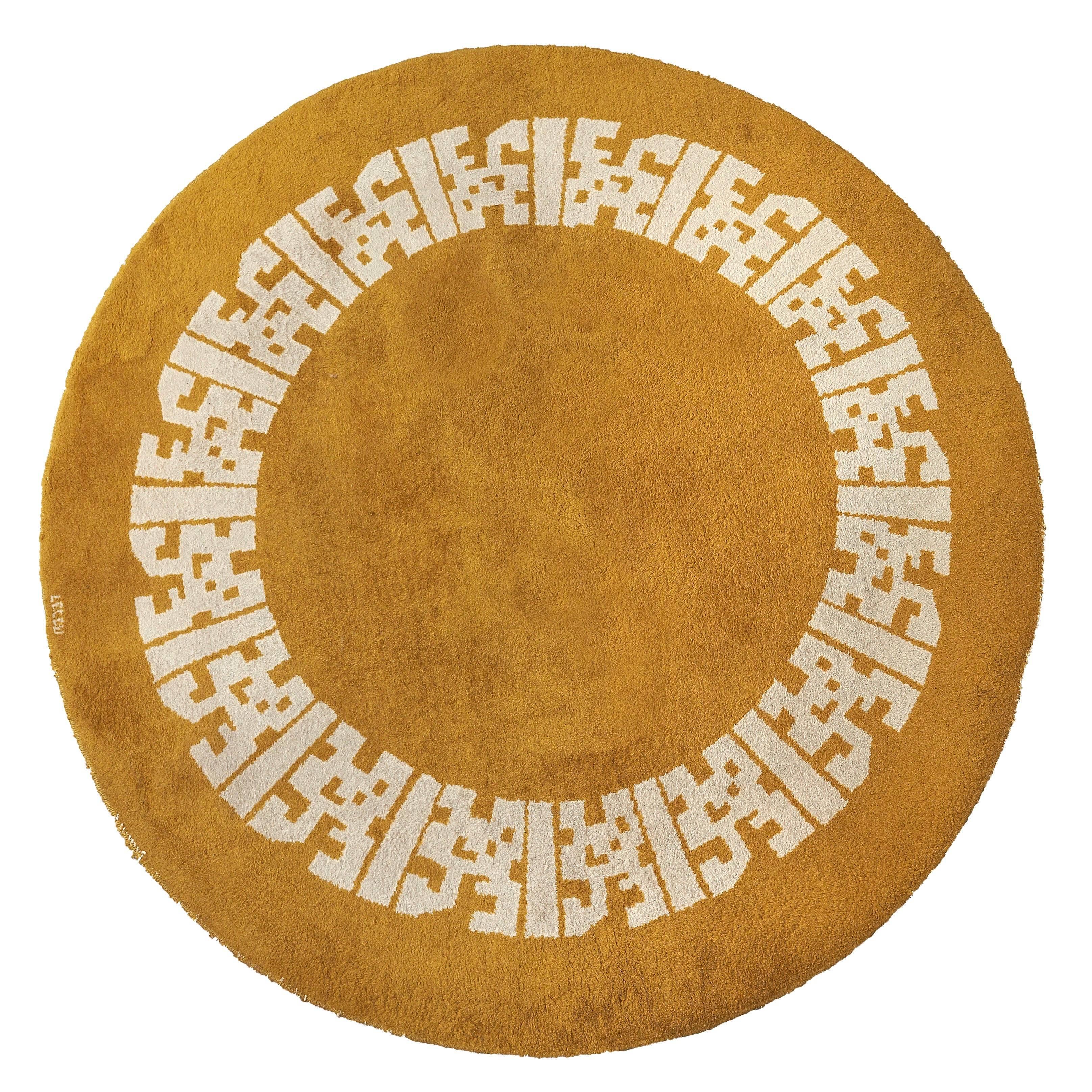A round woolen carpet with white geometrical decoration on a yellow background.
Signed 'LELEU' in the thread.
