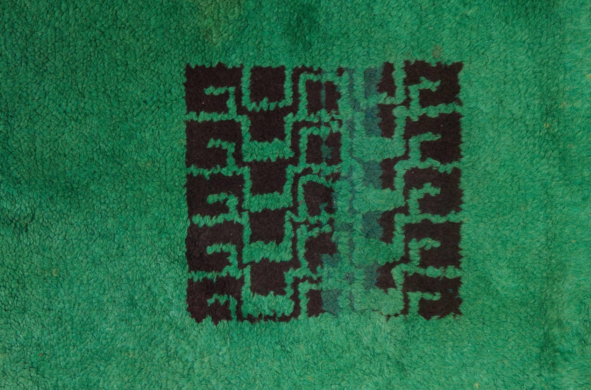 Un rare grand tapis rectangulaire en laine nouée avec une décoration géométrique noire sur un fond vert. Signé du monogramme 