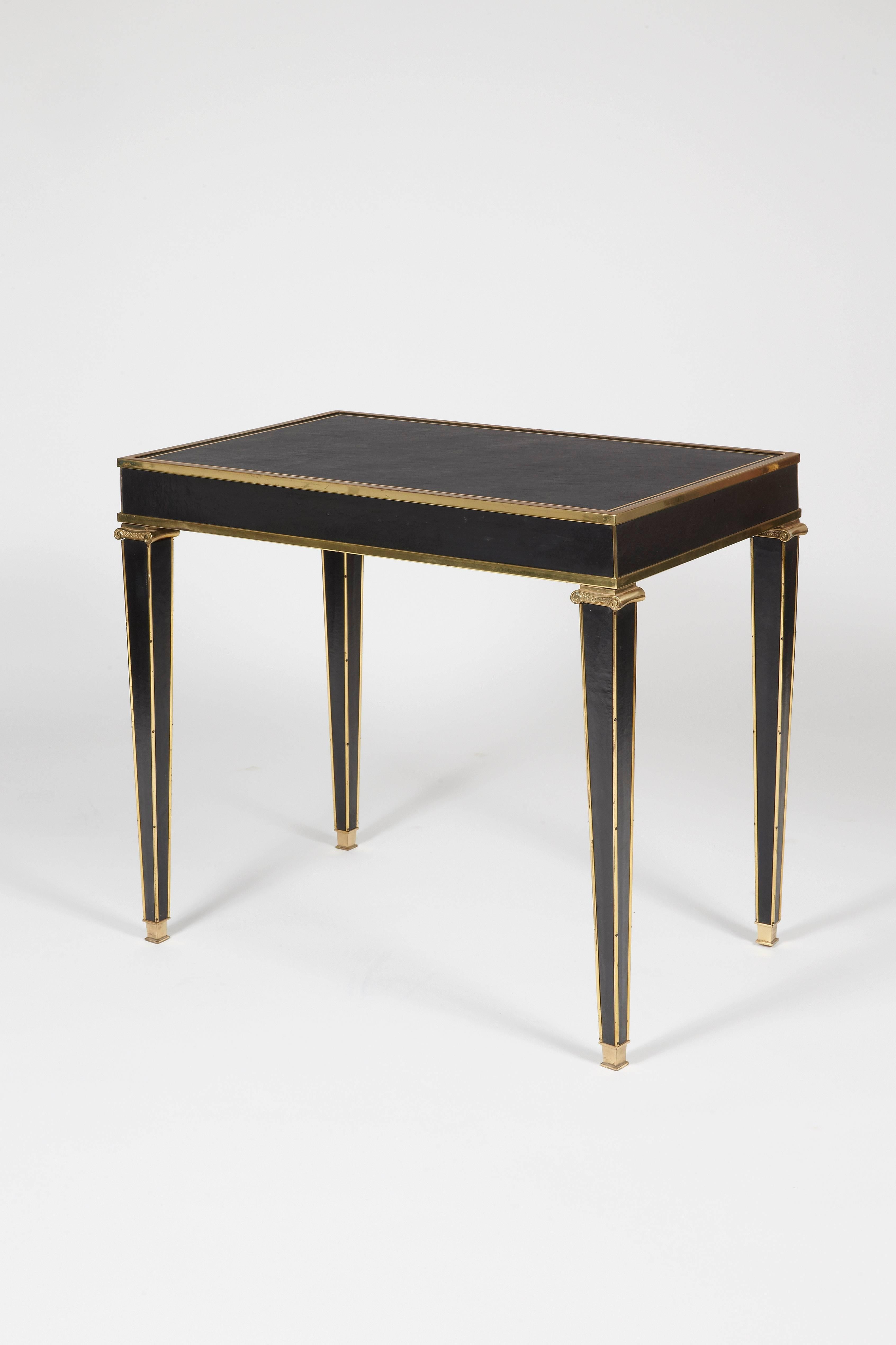 Patinated black leather-covered wood, rectangular top on four tapered legs decorated on the upper part top with gilded brass wisps.

This centre table or console was supposedly realized at the demand of Comte de Elda, as part of the grandiose