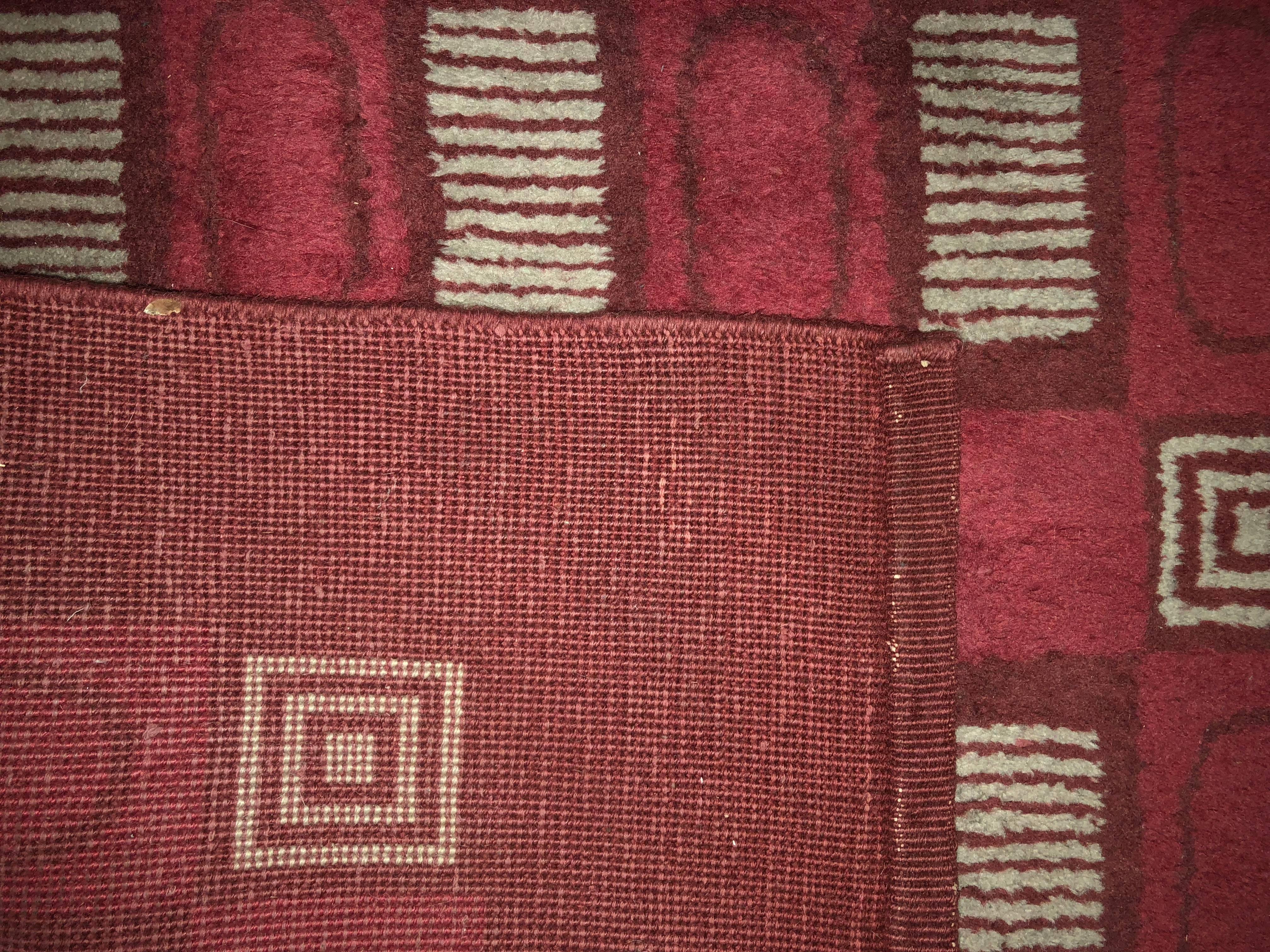 A Knotted woollen rug with red background, with beige geometrical patterns.

Provenance : Private Collection, an apartment Quai d'Orsay decorated by Jansen, Paris.