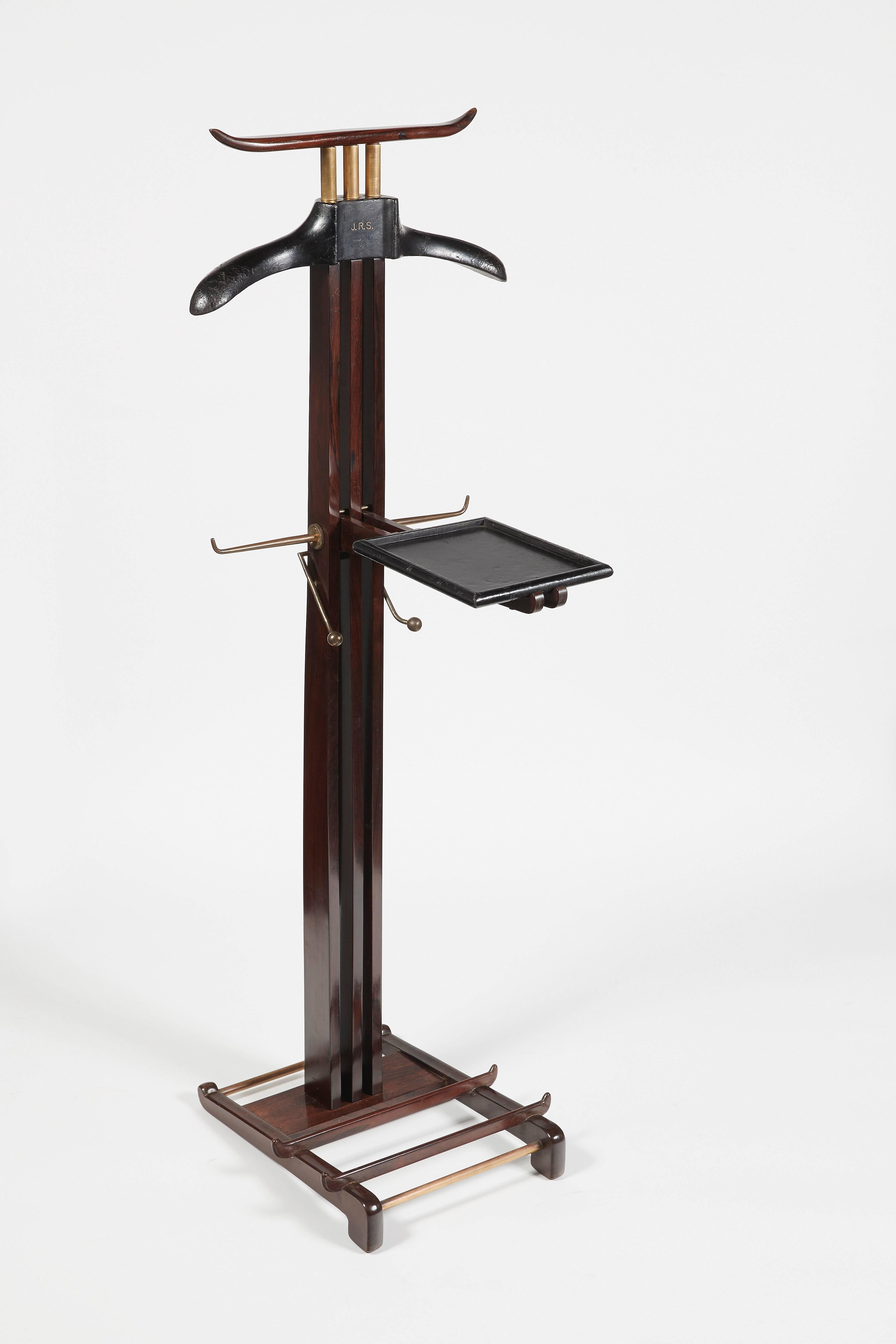 Night valet with coat rack and removable shelf entirely covered in black leather, held in varnished wood uprights and ending with tubular brass crosspieces forming shoe racks.

Iconic piece born from the collaboration of Paul Dupré-Lafon and the