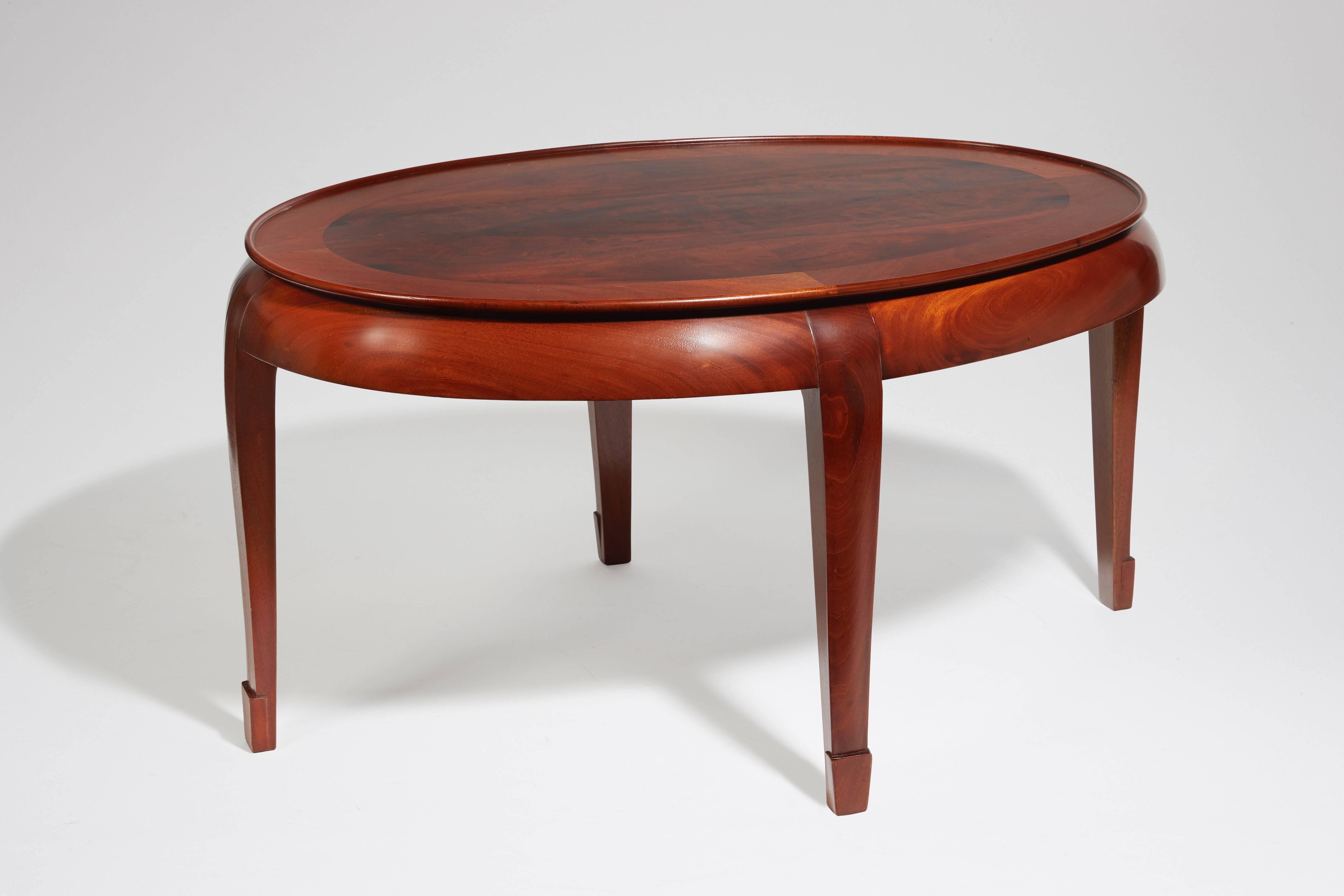 A Mahogany coffee table, oval shaped top. Stamped with the monogram stamp of the Compagnie des Arts Français.
