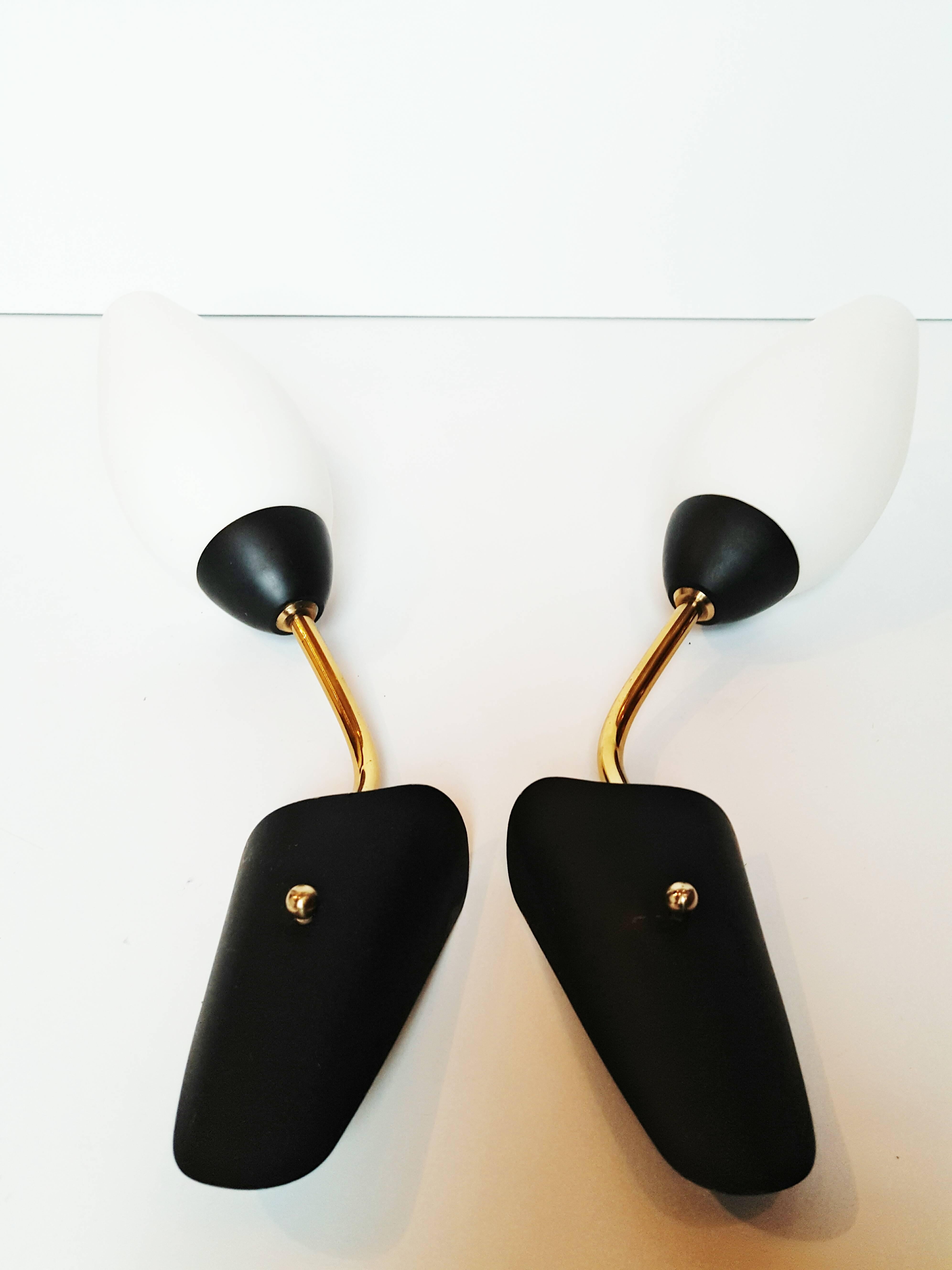 A great pair of original 1950s Italian wall lights coped of an aged brass and black enamel frame with white frosted cone glass shades.
In very good vintage condition.