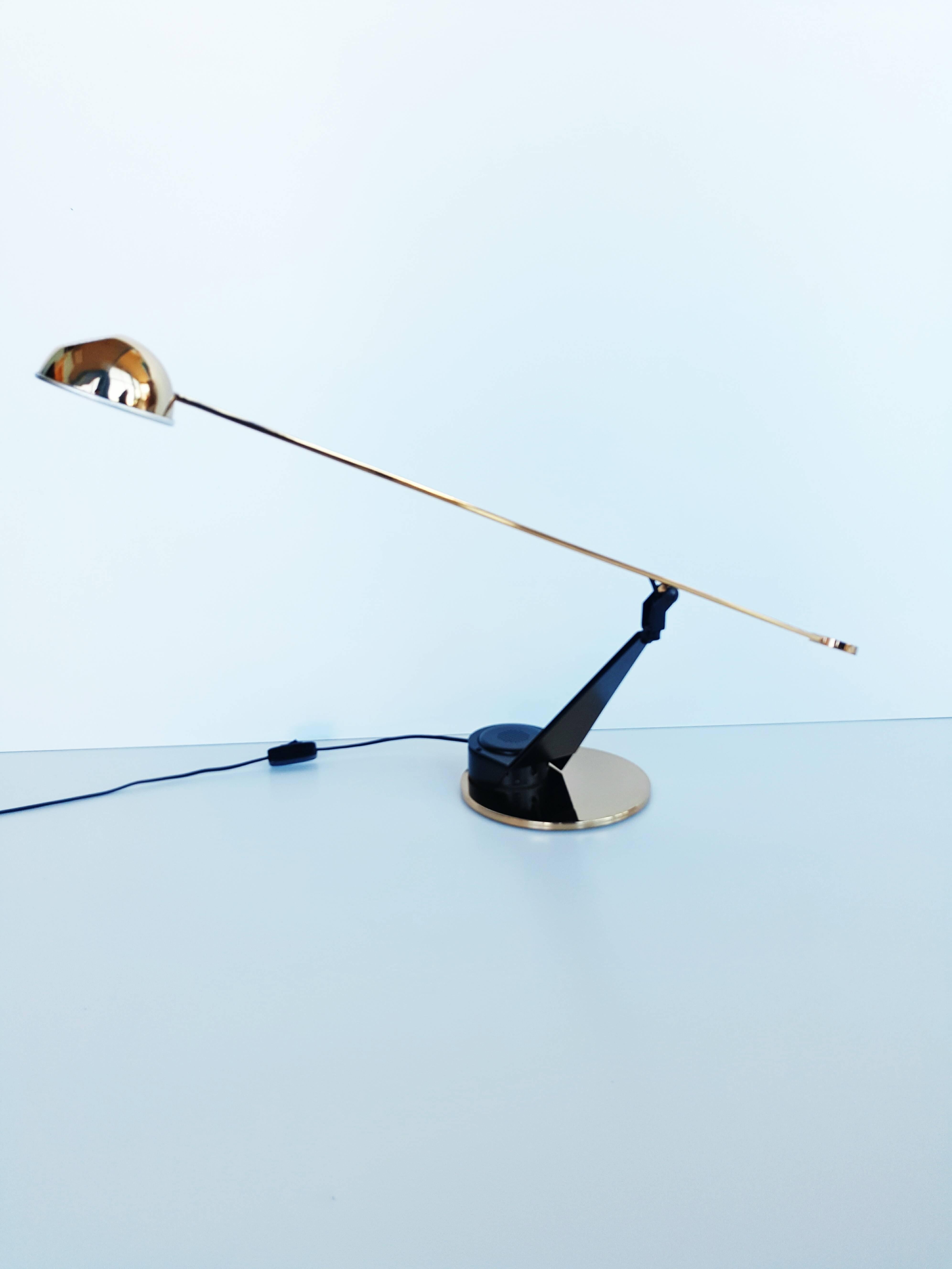 Desk lamp of Spanish home Fase, 1980. Etiquette this year on the underside of the base. Consisting of a counterweight arm hanging in balance, golden color. From a semi-spherical baffle black metal. The finishes are shiny golden. black felt on the