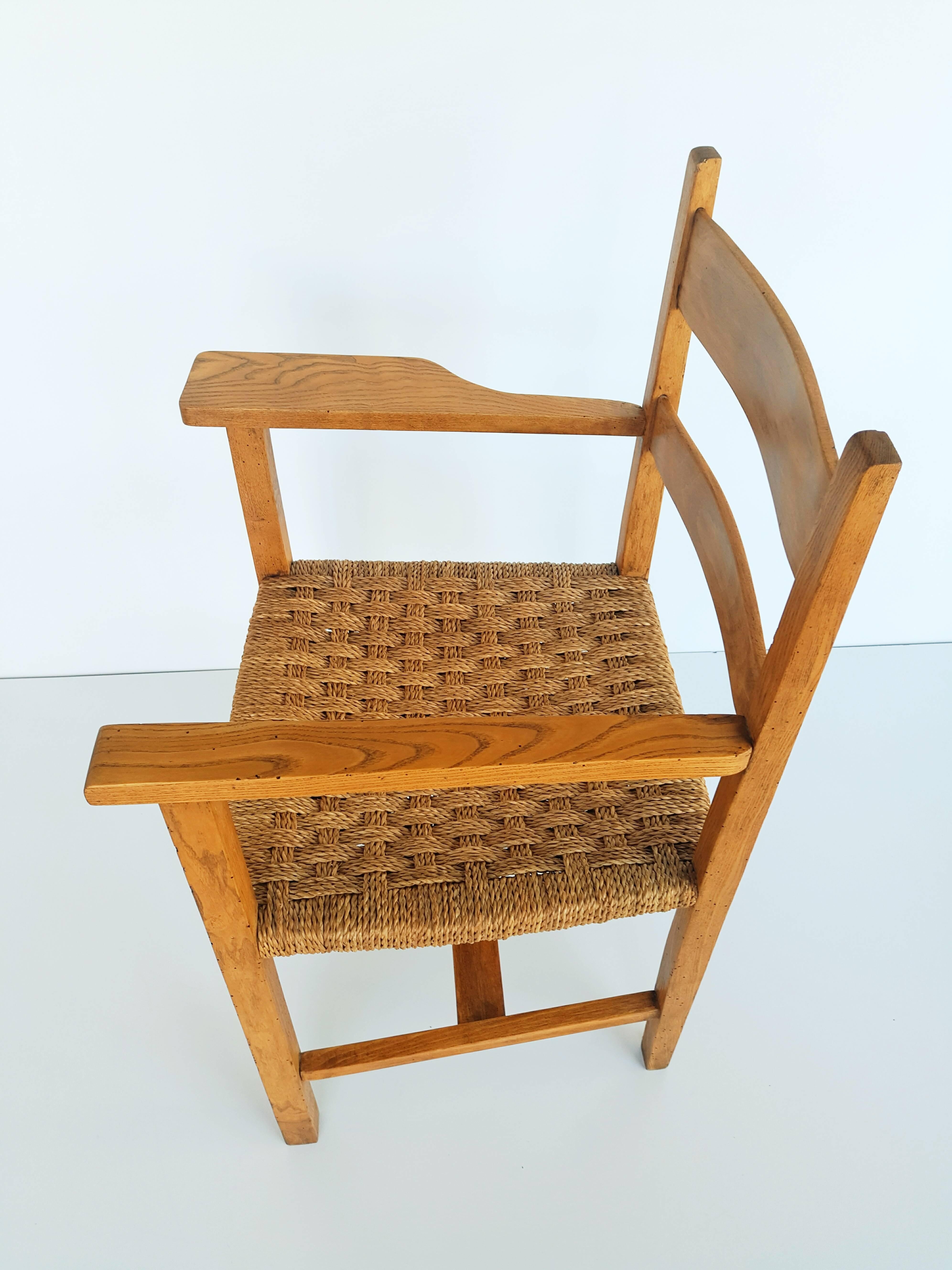 Beautiful and rare 1950s oak and raffia woven armchair, with one of two largest armrests. In perfect vintage condition.