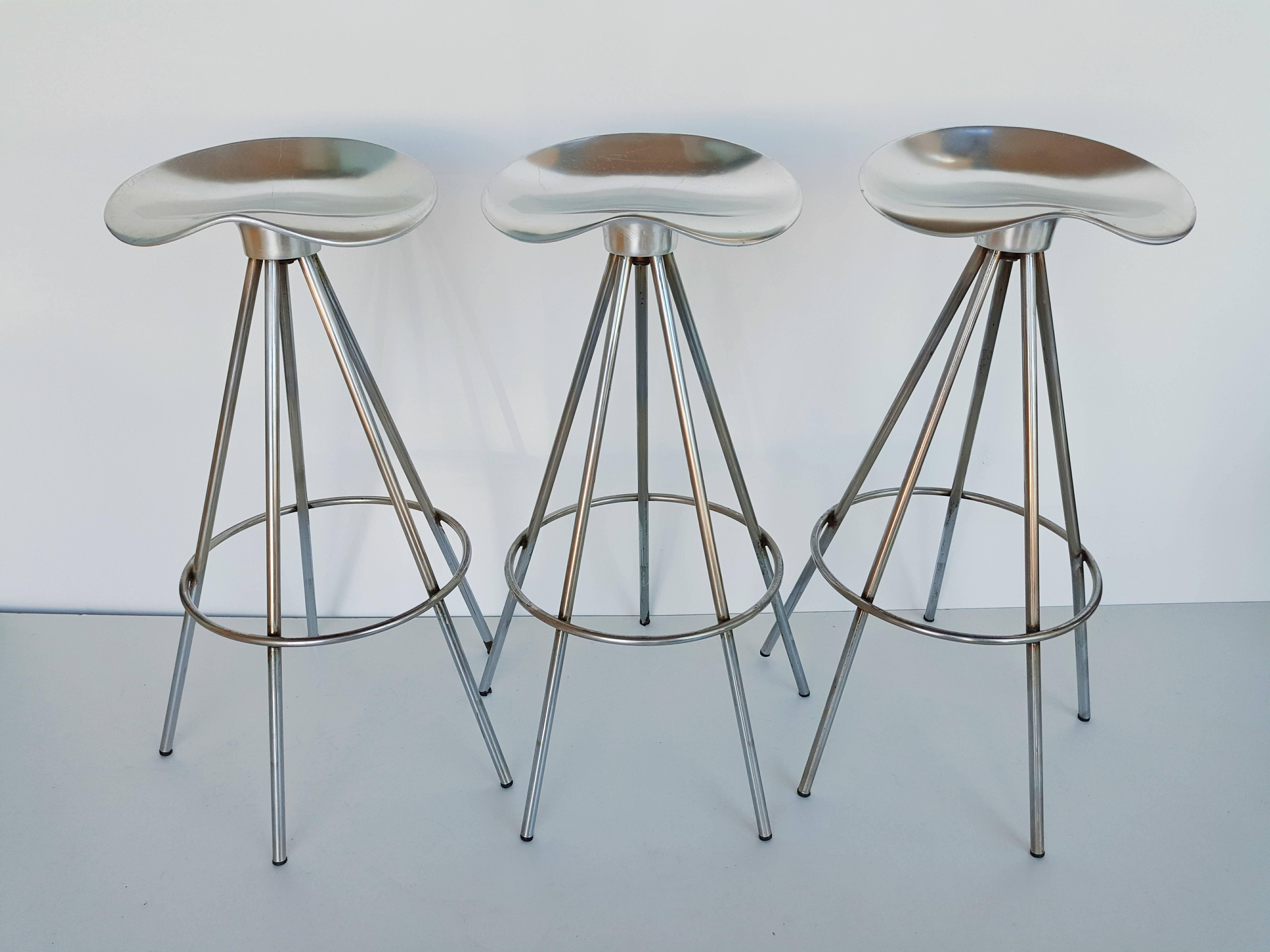 Set of three first edition bar stools designed by Pepe Cortes and made in Spain by Amat-3 for Knoll. Aluminum saddle-like seats which swivel and chrome frames. In very good vintage condition. 
Seat dimensions (cm): 36 x 34. Two set of three