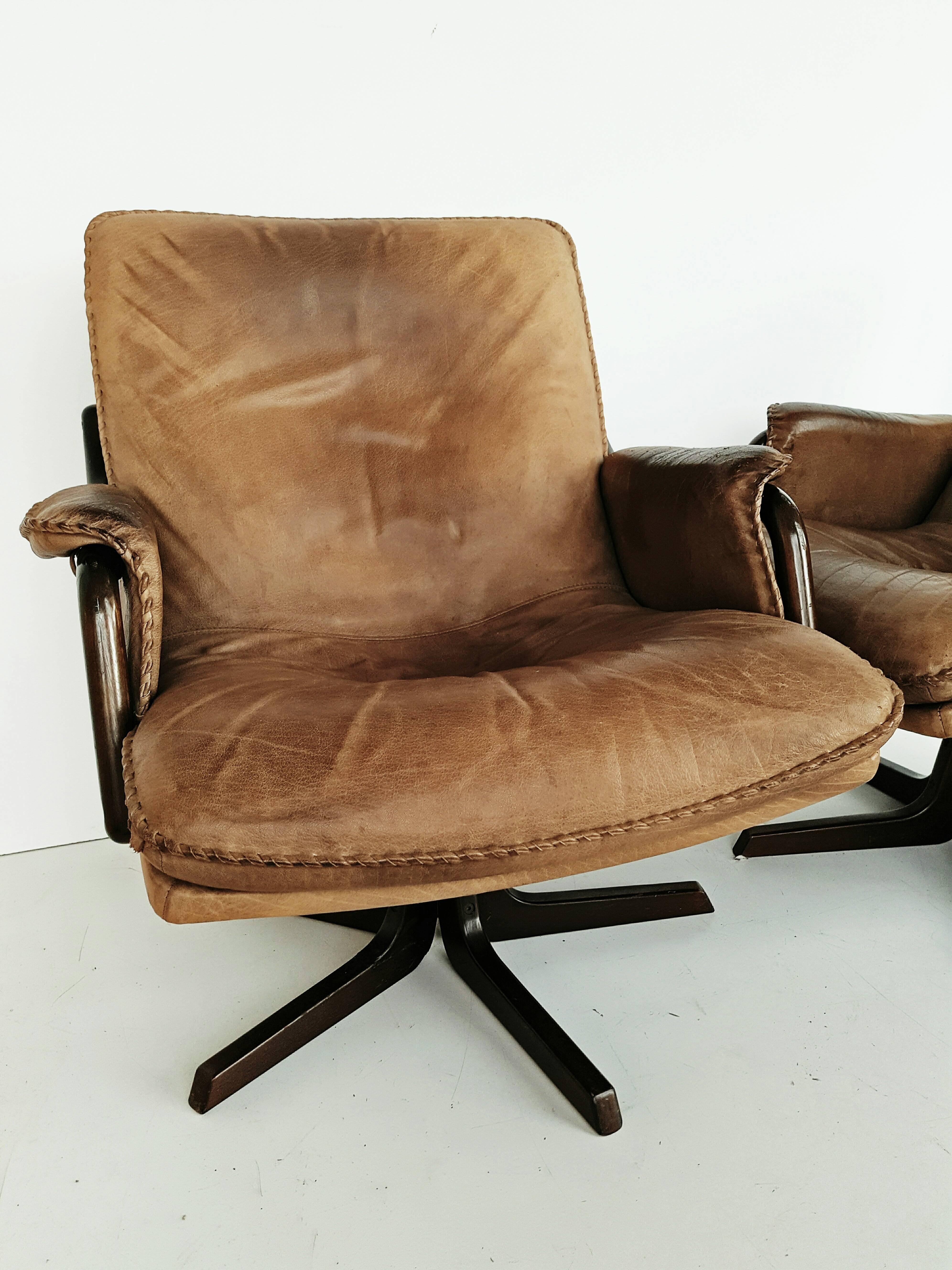 Rare pair of Mid-Century swivel armchairs in a beautiful patined taupe leather, manufactured in Denmark in the 1960s. Rosewood legs and armrests. In very good vintage condition.