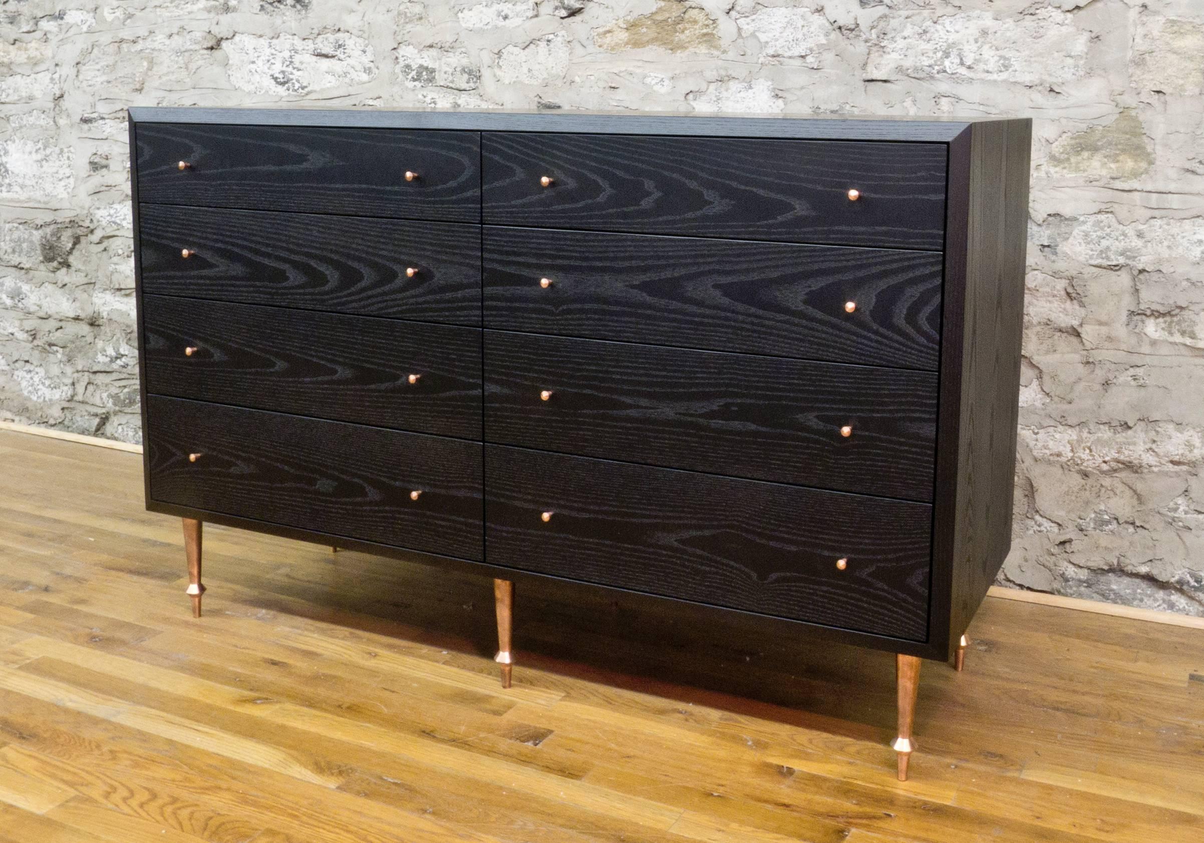 As shown:
Solid blackened ash with turned copper legs and drawer pulls and solid walnut with turned brass legs and pulls.
Fabric lined drawers by request at an additional fee.
Waterborne or oil and wax finish.
Dimensions: 36” H x 56” W x 20”