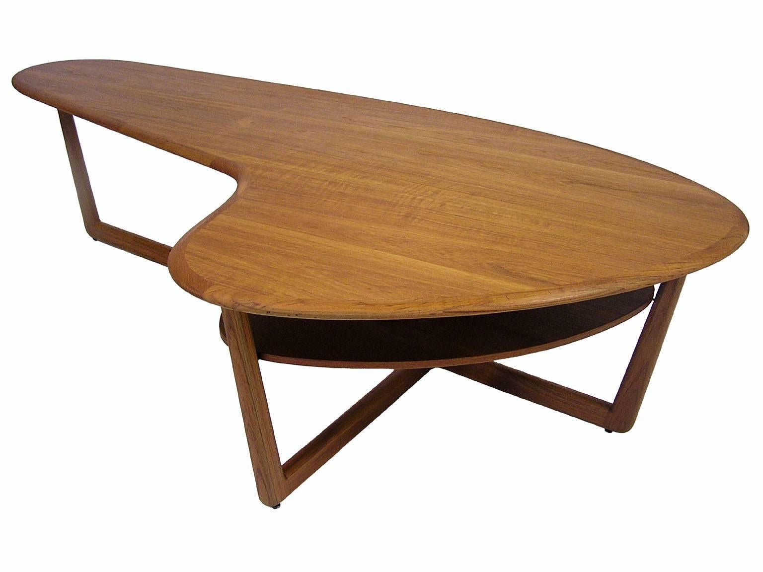 An amazing kidney shaped teak coffee table from the 1960s Mid-Century Modern era by Interior form furniture limited of Canada. Gorgeous craftsmanship throughout with a solid tapered edge, T-bar style base and biomorphic shaped lower shelf. Table has