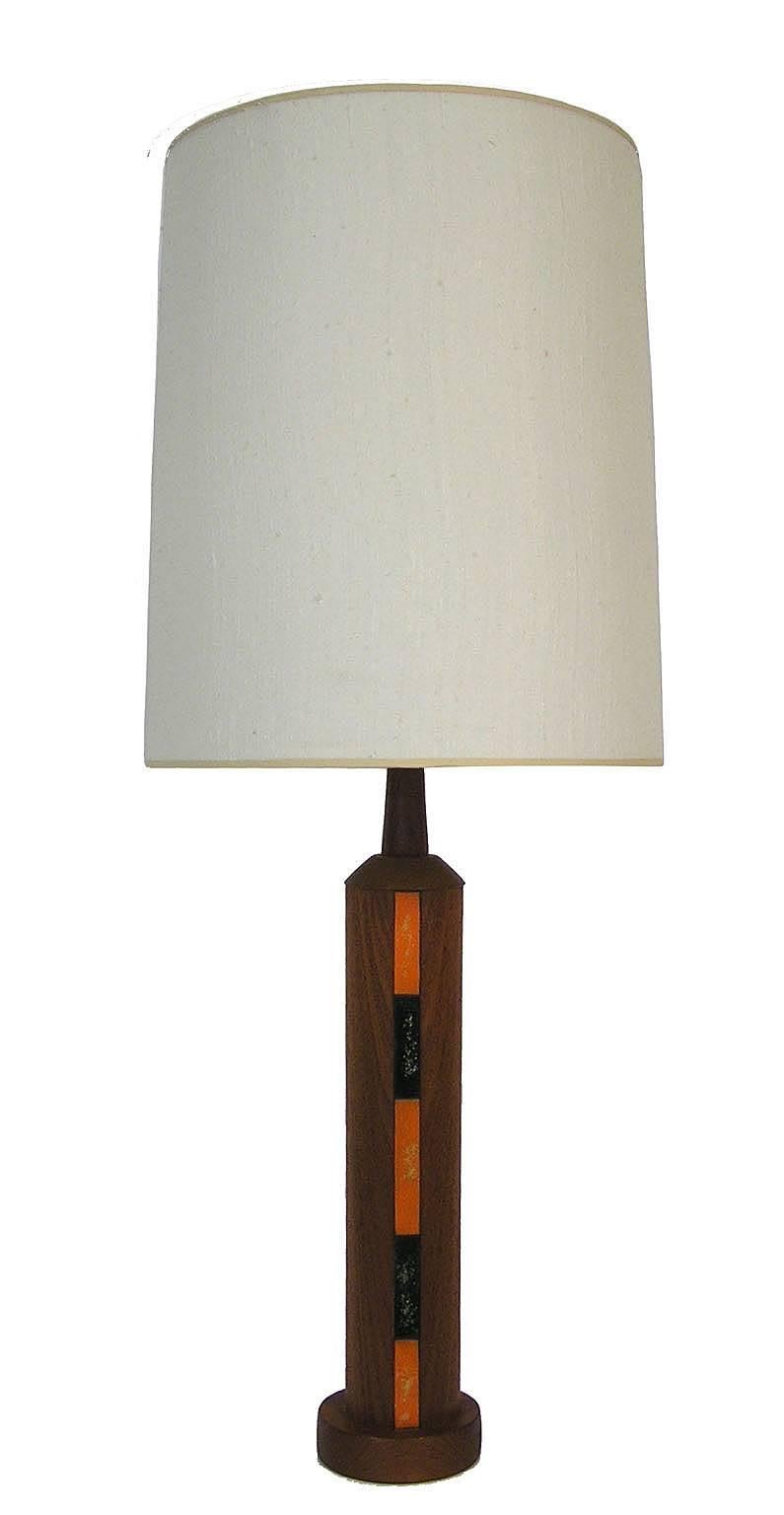 This unique pair of Danish modern solid teak table lamps date from the 1960s. Both lamps feature three striking strips of painted metal applique in black and orange. Each lamp features a three way tri-light switch, milk glass reflector and a raw