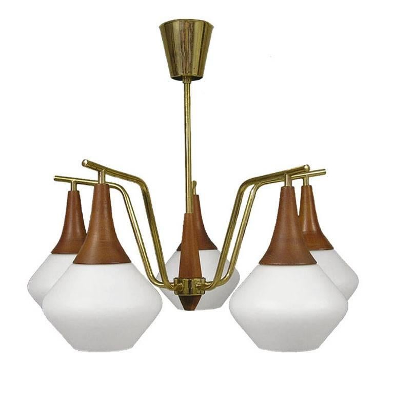 A gorgeous five-light teak and brass chandelier with shaped glass shades from the 1950s Danish modern era. Chandelier has been rewired to conform to North American standards and is in excellent working condition. A stunning example of Scandinavian