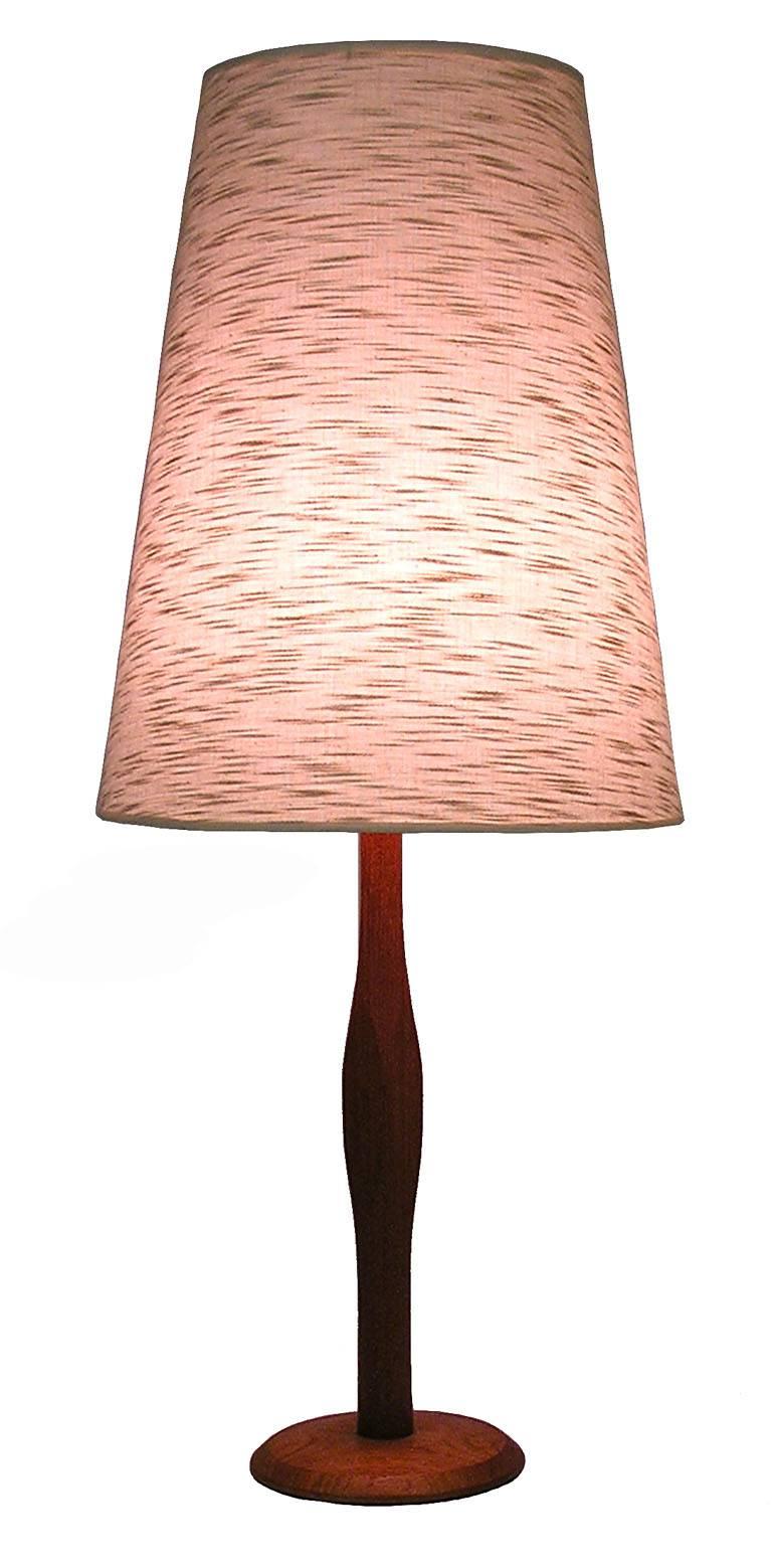A solid teak table lamp from the 1960s. Danish Modern inspired craftsmanship throughout featuring a sculpted teak shaft set on a 7 3/4