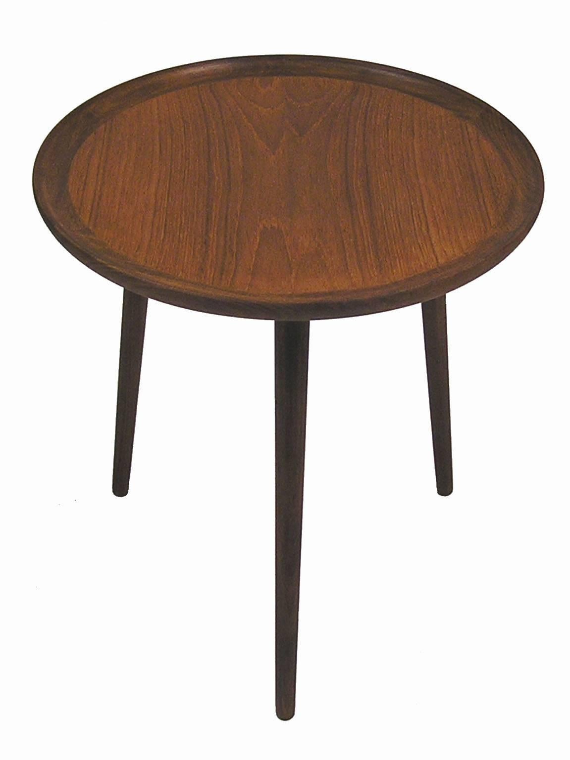 A gorgeous round tripod-leg teak occasional side table from the 1960s by Danish Mid-Century Modern designer Anton Kildeberg. Features a beautifully sculpted solid teak trim with tapered conical legs and is in excellent newly refinished condition.