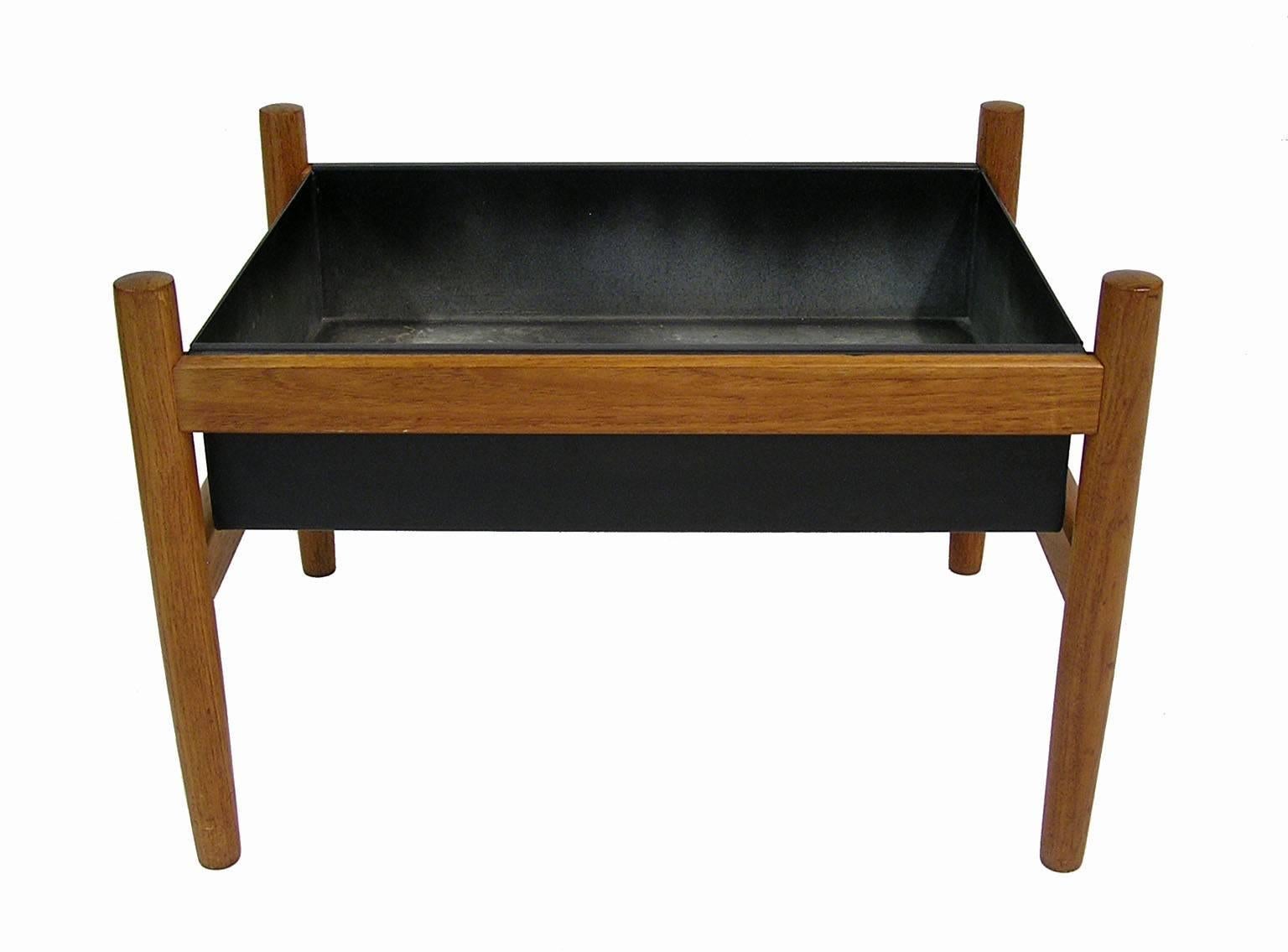A small teak planter from the 1960s by Spøttrup of Denmark. Stylish Scandinavian Modern era lines with original black metal insert that slots comfortably into the solid teak frame. Has some light surface wear from use to the interior of the insert
