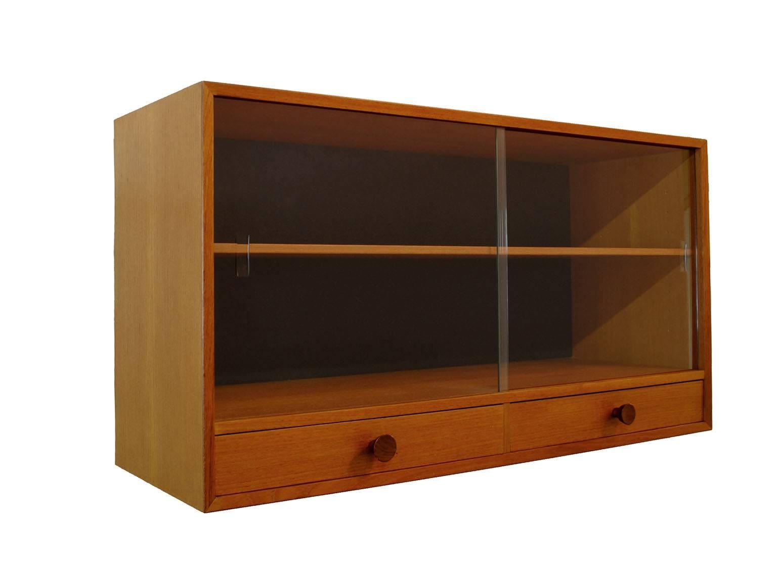 A stylish teak hutch from the 1960 Scandinavian modern era designed by Nils Jonsson for Troeds of Sweden. Well constructed featuring two lower drawers with dove-tailed joinery, glass sliding doors and an adjustable shelf. Can either sit freely on