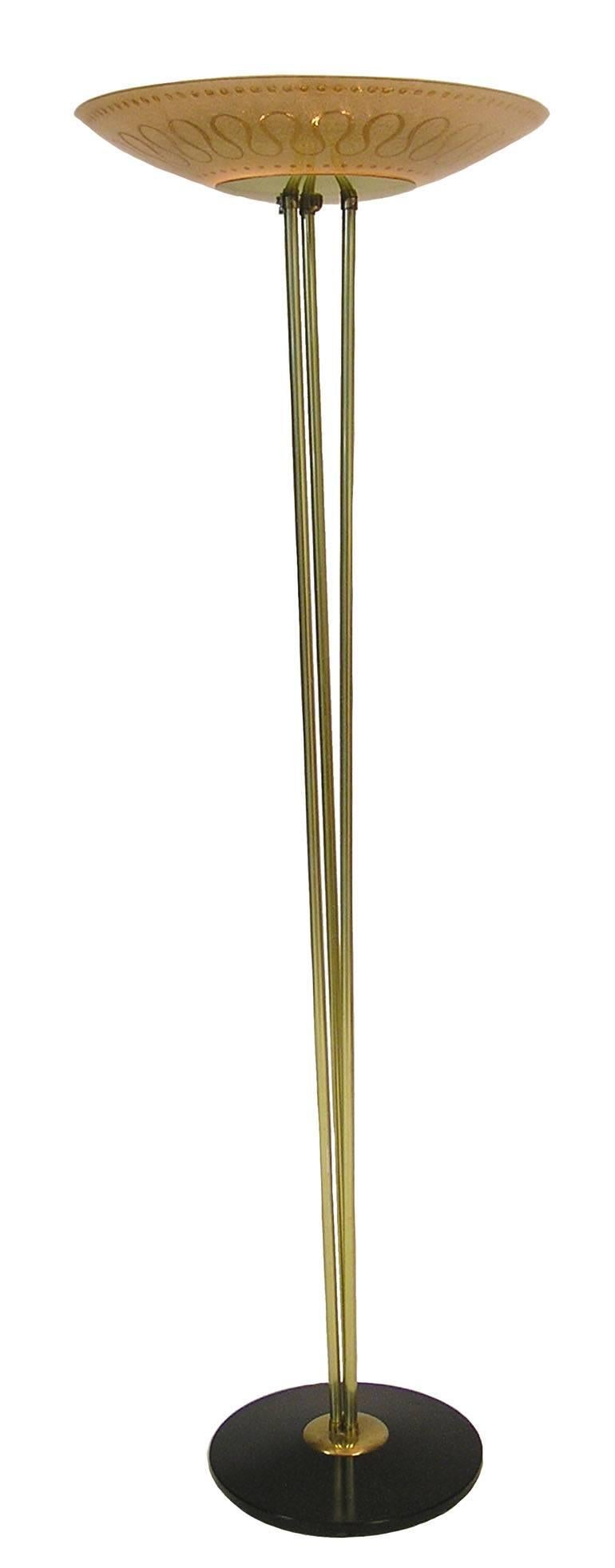 A stunning torchiere style floor lamp from the 1950s by Gaetano Sciolari for Stilnovo of Italy. Uniquely designed featuring a textured amber glass shade set on a slender three post brass stem and mounted on a coated black metal elliptical base.