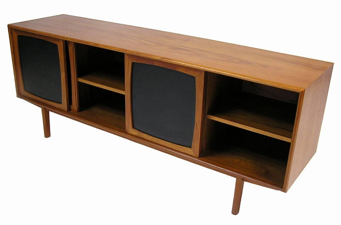A fabulous low teak sideboard from the 1960s by Inter-Continental-Design of Canada. Stylish Scandinavian Modern inspired lines featuring Naugahyde paneled sliders, adjustable shelving and a concealed bank of four drawers along the left side. Top two