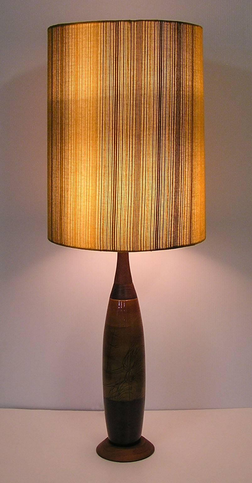 A gorgeous ceramic pottery table lamp from the 1960s Mid-Century Modern era with original multi-toned fabric shade.  Designed with a tapered slender form and featuring a neutral toned ceramic body that is decorated with hand-painted detailing. 