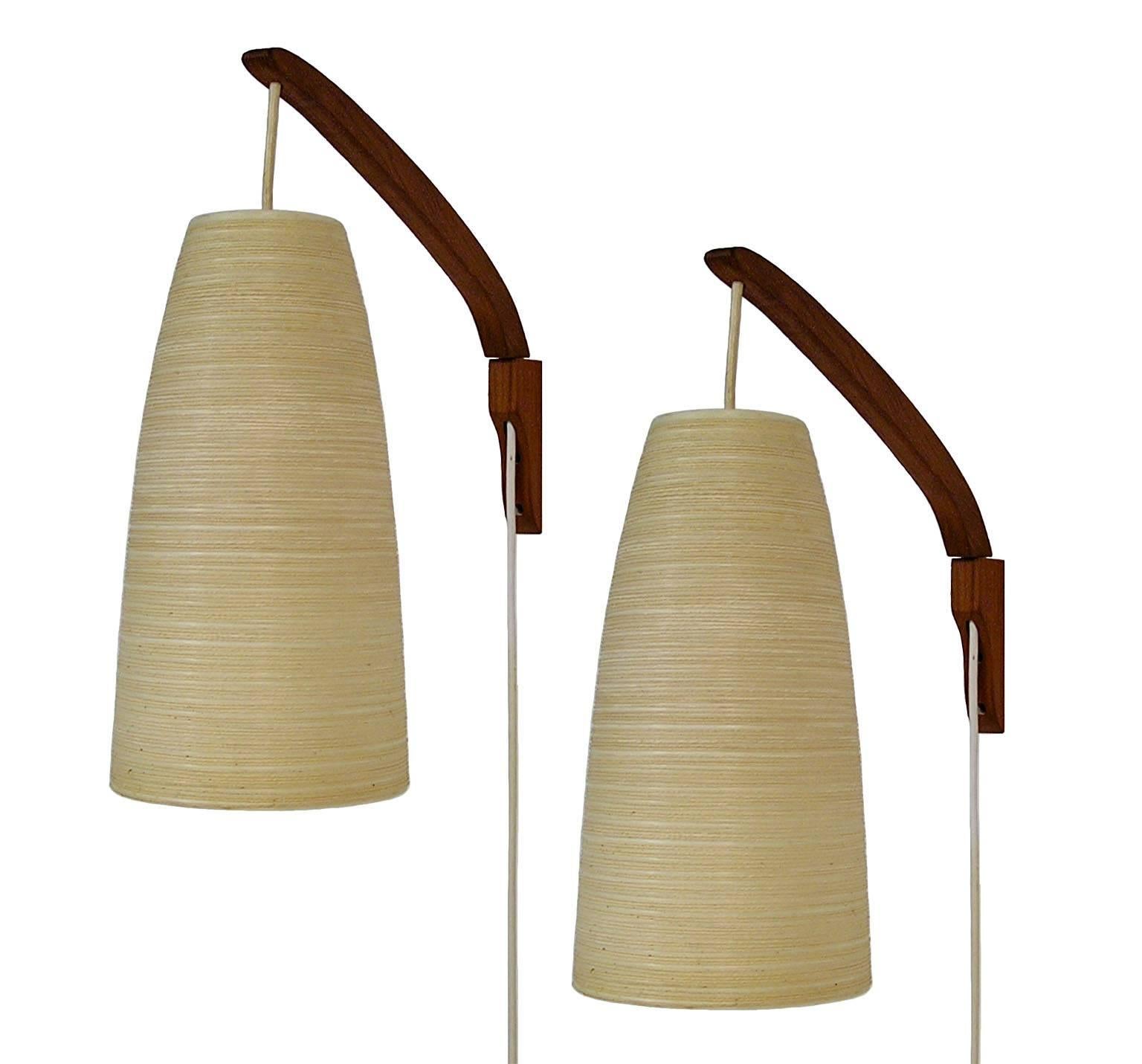 A beautiful pair of teak wall sconces by Gunnar and Lotte Bostlund. Stylish Scandinavian Modern inspired design featuring a unique beehive shaped shade made of fiberglass and jute with an inline thumb switch to power the lamps on and off. The solid