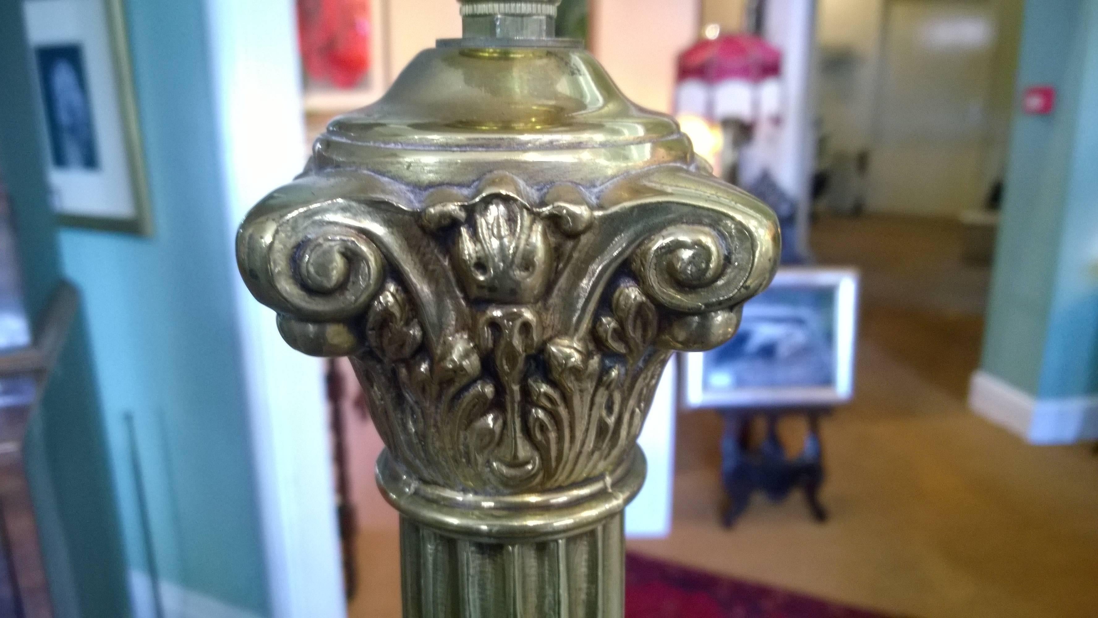 Brass table lamp in the form of a Corinthian column atop an Art Deco style platform base, circa 1930. Measures: 12" diameter x 31" height. The lampshade(s) are newly handmade silks by the same maker as provides the shades for Downton