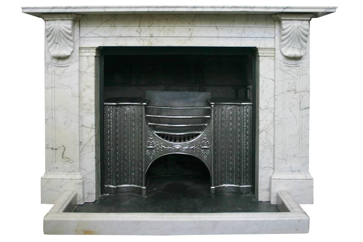 Early 19th century Regency Carrara marble fireplace surround with well carved acanthus corbels supporting the shelf. The jambs and frieze benefit from fielded panels, circa 1830. Pictured with a Georgian cast iron grate and marble fender, sold