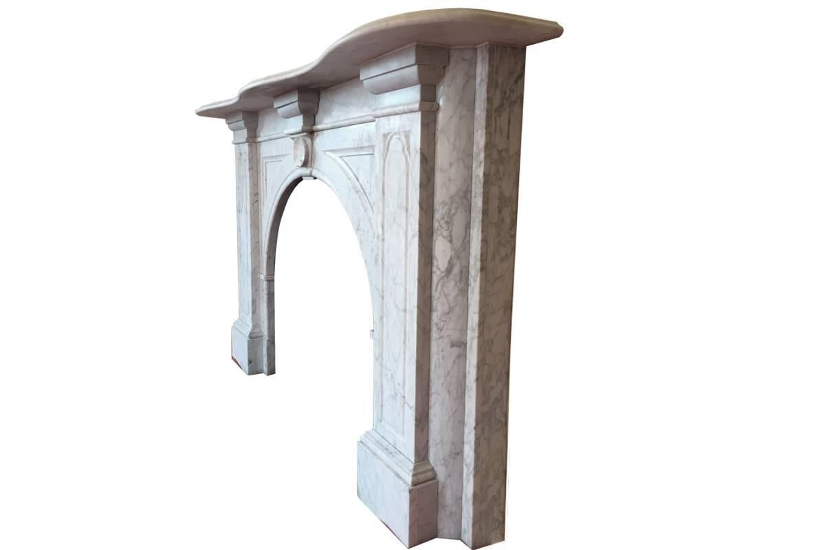 Large Victorian Carrara marble fireplace surround with arched aperture. Fielded panels to the spandrels which are supported by a keystone with clam shell carved in high relief. To the jambs simpler panels of good shape all below a deep serpentine