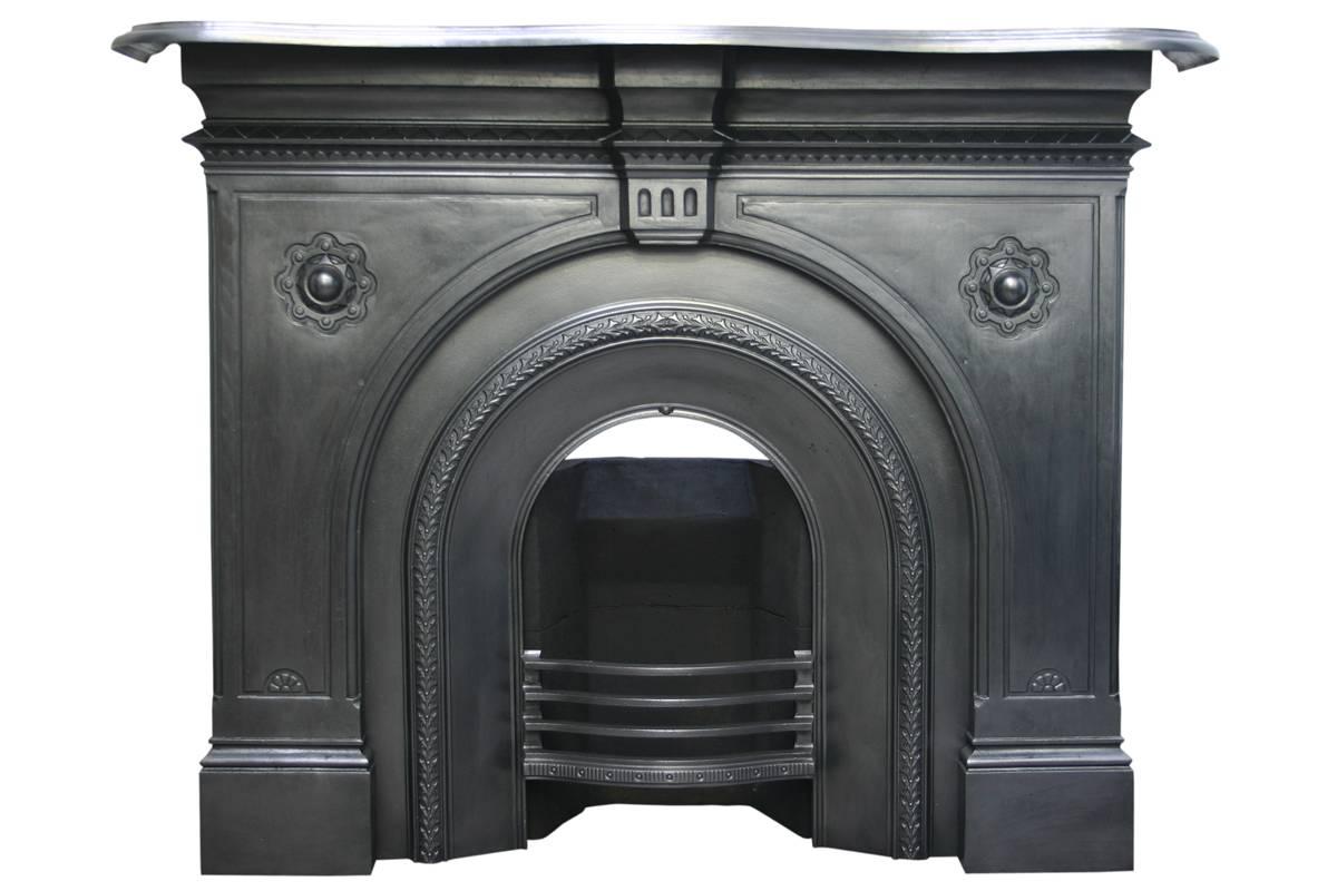 19th century Victorian cast iron fireplace surround with arched aperture. The simple paneled legs centered with ornate bosses and supported by a fluted keystone below a serpentine shaped shelf. Registration date mark of 16th June 1877.
Pictured