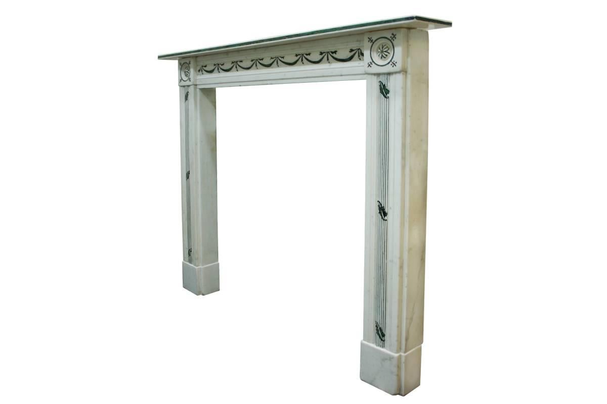 Rare Early 19th century Regency Statuary Marble and scagliola fire surround. The straight edged shelf is detailed with black and greens scagliola, below which the carved frieze is also inlaid with bows and swags, flanked by carved roundels with