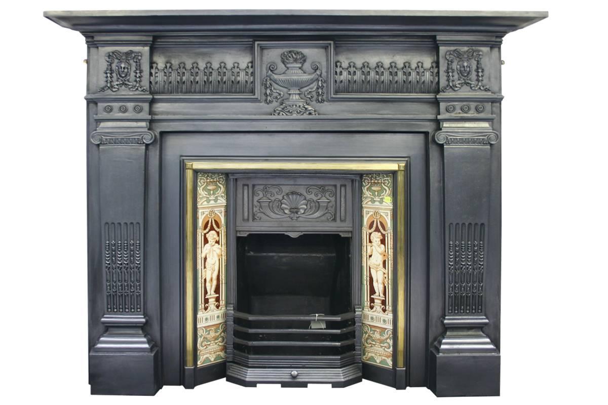 Large classical antique Victorian cast iron fireplace surround, female heads adorn the capital and an urn to the frieze. Pictured with a brass framed tiled grate, sold separately.