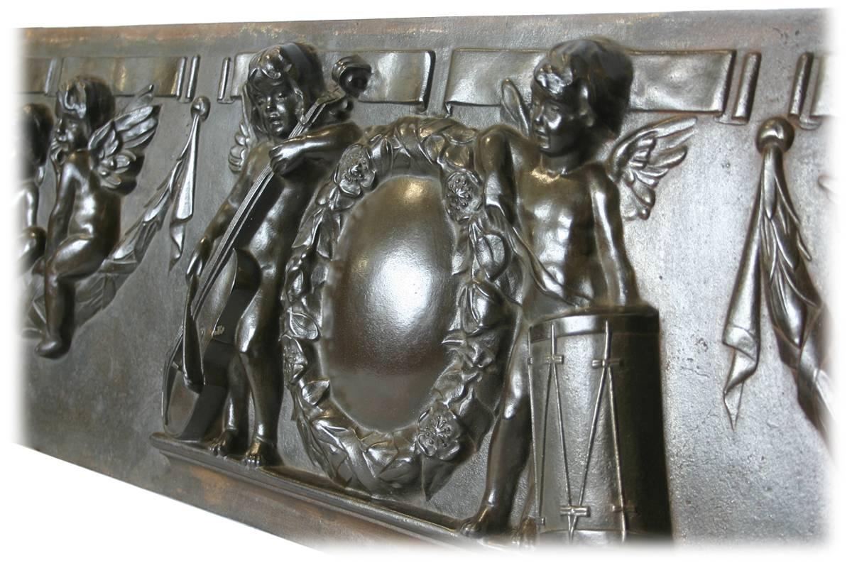 Large and unusual 19th century decorative iron panel depicting cherubs practicing the arts. To the center two cherubs are holding a drum and cello leaning against a large wreath. Flanked on either side by four further cherubs sitting on sways of