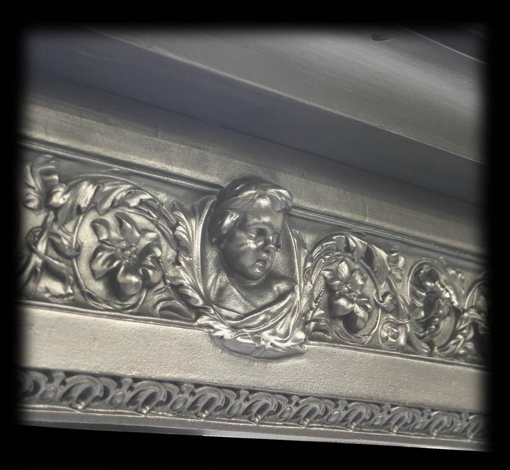 Antique Victorian ornate cast iron fireplace surround. The legs and frieze decorated with acanthus scroll and flowers, to the centre of the frieze a cherubs head and shoulders.