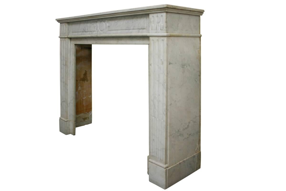 Antique 19th century Carrara marble fire surround in the Louis XVI style, circa 1880. Tapering fluted and reed legs terminate in square capitals also with flutes and reed.
Images prior to restoration. This chimneypiece is awaiting restoration,