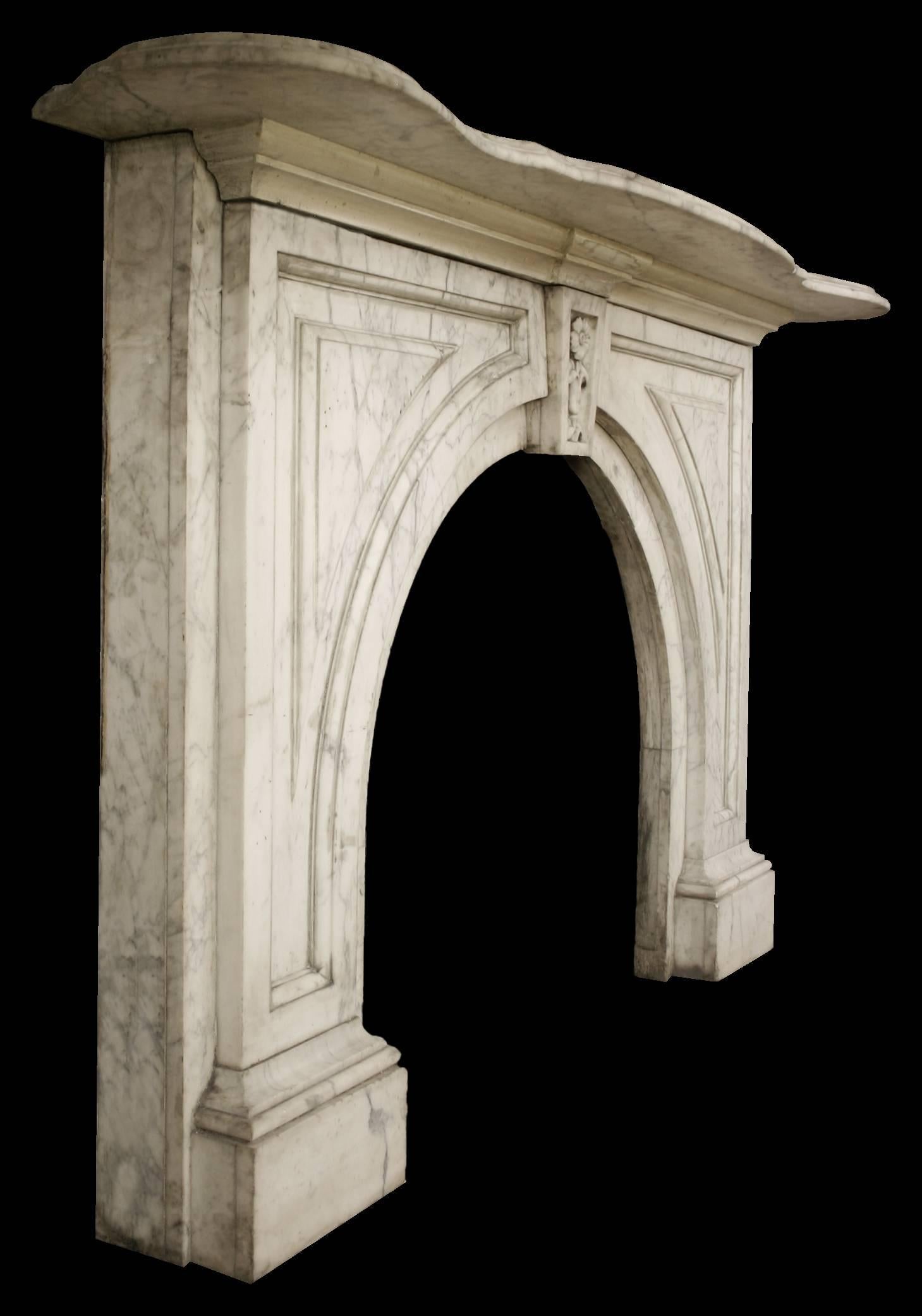 Large antique mid-Victorian Carrara marble fireplace surround with arched aperture. Fielded panels to the spandrels and attractive floral keystone.

Images prior to restoration. This chimneypiece is awaiting restoration, please enquire as to the