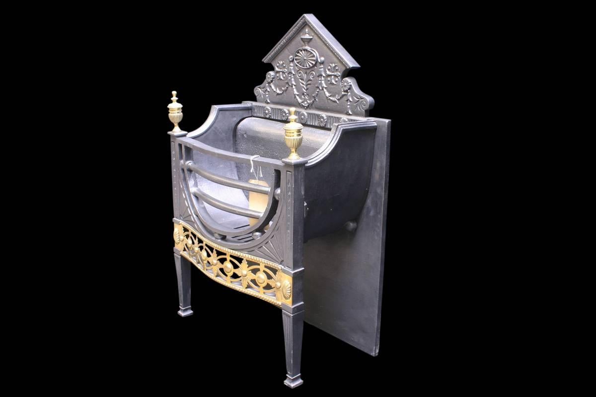 Fine antique mid-Victorian dog grate of elegant proportions in the neoclassical style with a semi-circular grate and fan detail in the spandrels, above a classically fretted apron. The pedimented fireback is cast with a rosette and swags of