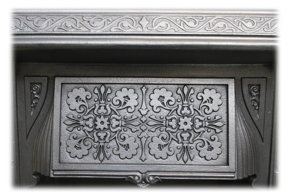 Reclaimed Victorian cast iron fireplace insert in the aesthetic manner with symmetrical blind fret detail to the canopy and frame, circa 1890.
Complete with an original set of antique fireplace tiles.

This grate has been finished the traditional