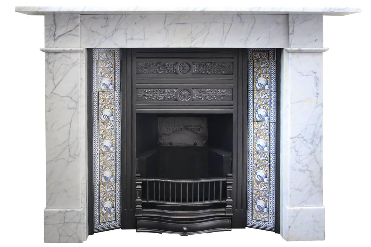 Reclaimed antique Victorian cast iron and tiled fireplace insert. The simple frame surrounds a taller than average run of antique fireplace tiles. To the centre is a deep flat canopy finely cast with flowering plants,
circa 1890. 

Seen with an