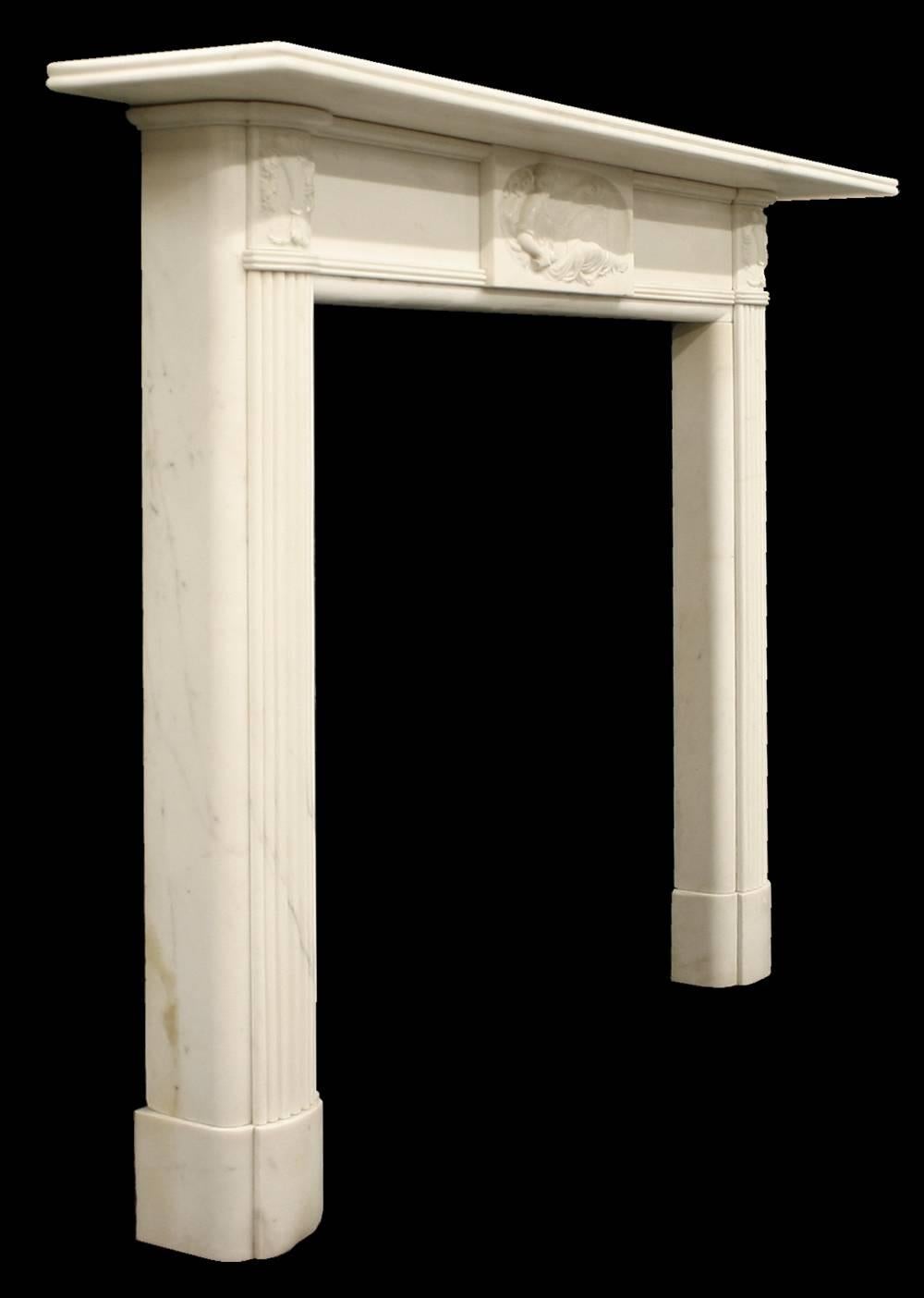 Fine and well executed antique Georgian statuary white marble fireplace surround. Reeded and curved leg faces sit atop curved plinths and terminate in finely carved capitals depicting a vase overflowing with fruit and grape vines. Below the reeded