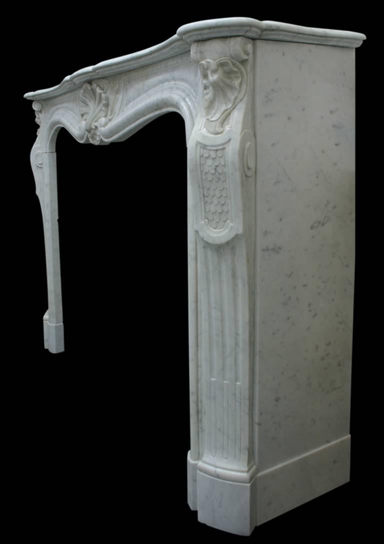 Restored 19th century Louis XV Carrara marble fireplace surround. The shaped frieze centered by a large carved shell sits between two canted cabriole jambs featuring scrolls and leaf to the capitals above well carved scale design and flutes,
circa