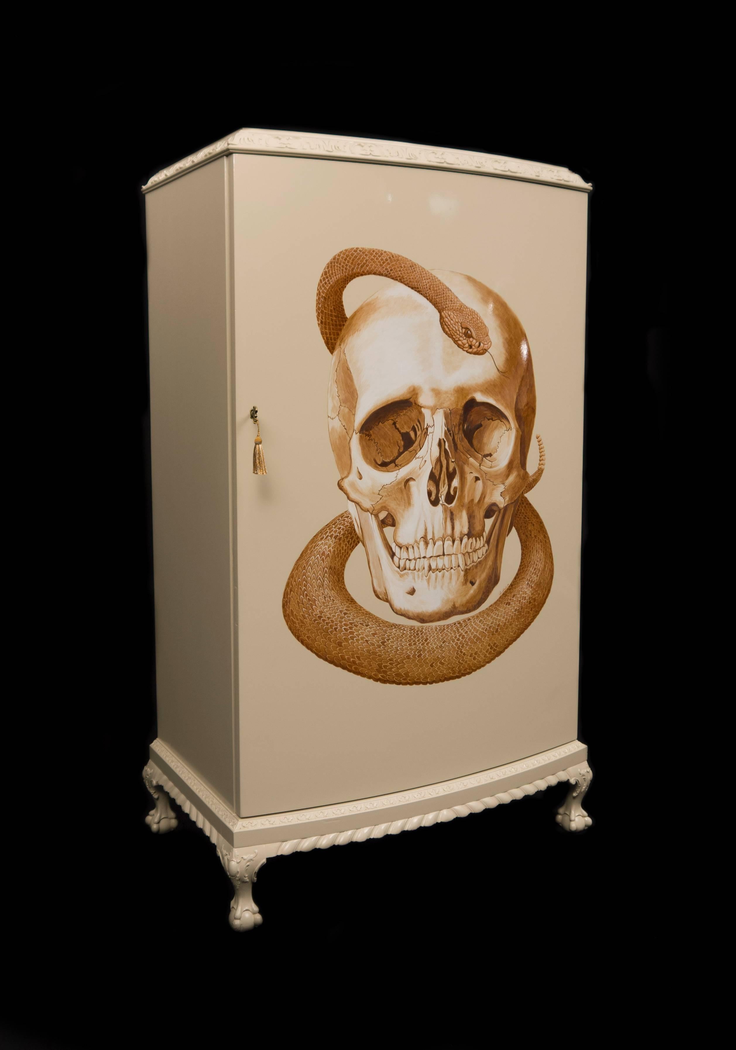 This early 20th century cabinet has been refurbished to a high standard and hand-painted as a celebration of symbolism in art. A unique blend of modern and Classic, the skull and snake symbolize the duality of life in death and rebirth down the ages