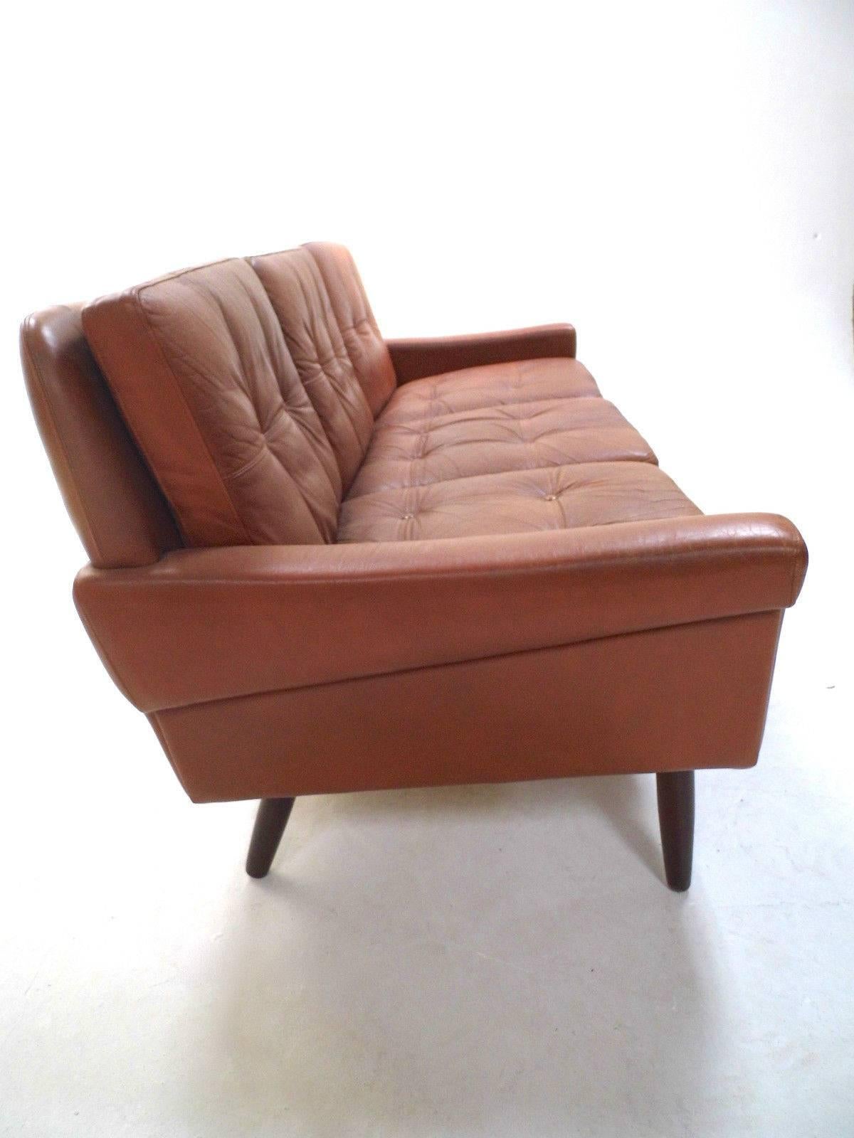A beautiful Danish tan brown leather three-seat sofa by Skipper Møbler, this would make a stylish addition to any living or work area. The sofa has buttoned cushions and padded armrests for enhanced comfort. A striking piece of Classic Scandinavian