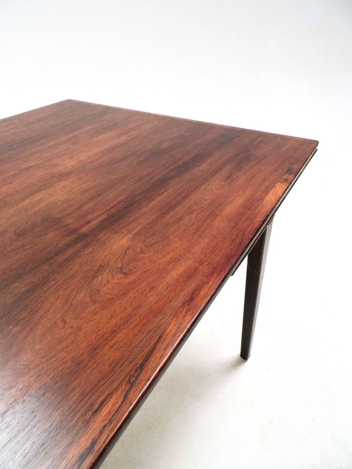 A beautiful Danish rosewood extending dining table designed by Johannes Andersen, this would make a stylish addition to any dining area. The table has two extension panels which fit discreetly below the top panel and can be pulled out when needed. A