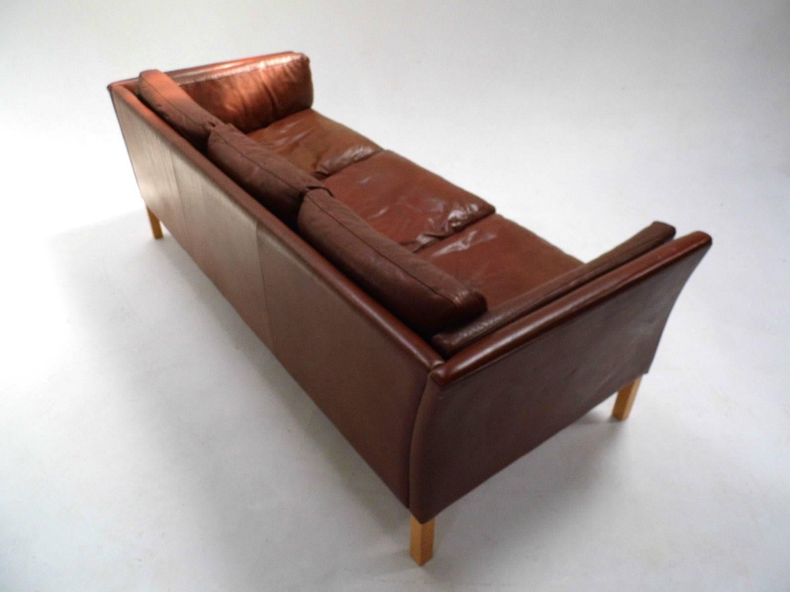 A beautiful Danish chestnut brown leather three-seat sofa, this would make a stylish addition to any living or work area. The sofa has wide cushions and padded armrests for enhanced comfort. A striking piece of Classic Scandinavian furniture.

The