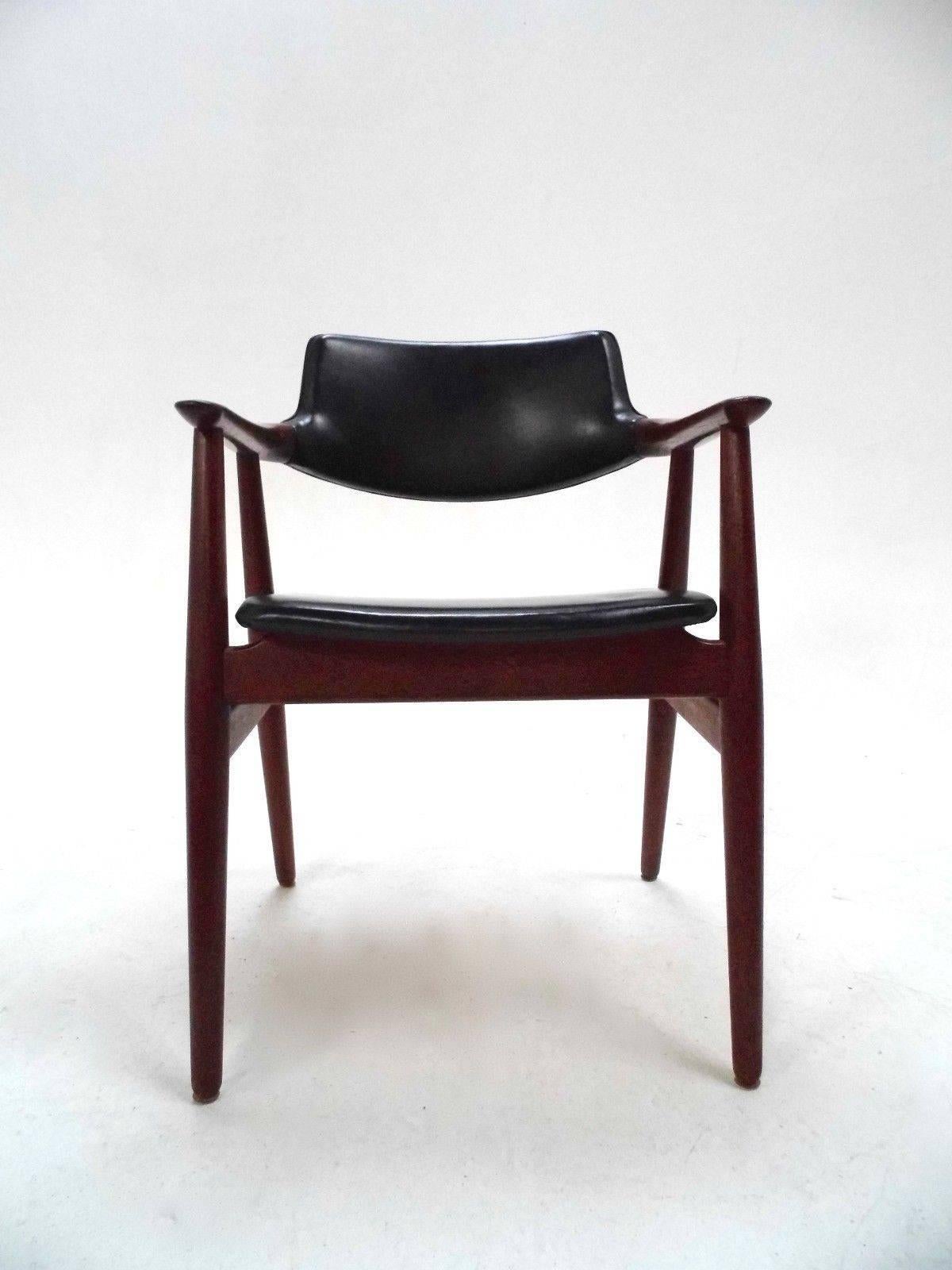 A beautiful teak and soft black vinyl desk chair designed by Erik Kirkegaard for Glostrup Mobelfabrik in the 1960s, this would make a stylish addition to any living or work area. The chair has a curved backrest and sculptured teak armrests for