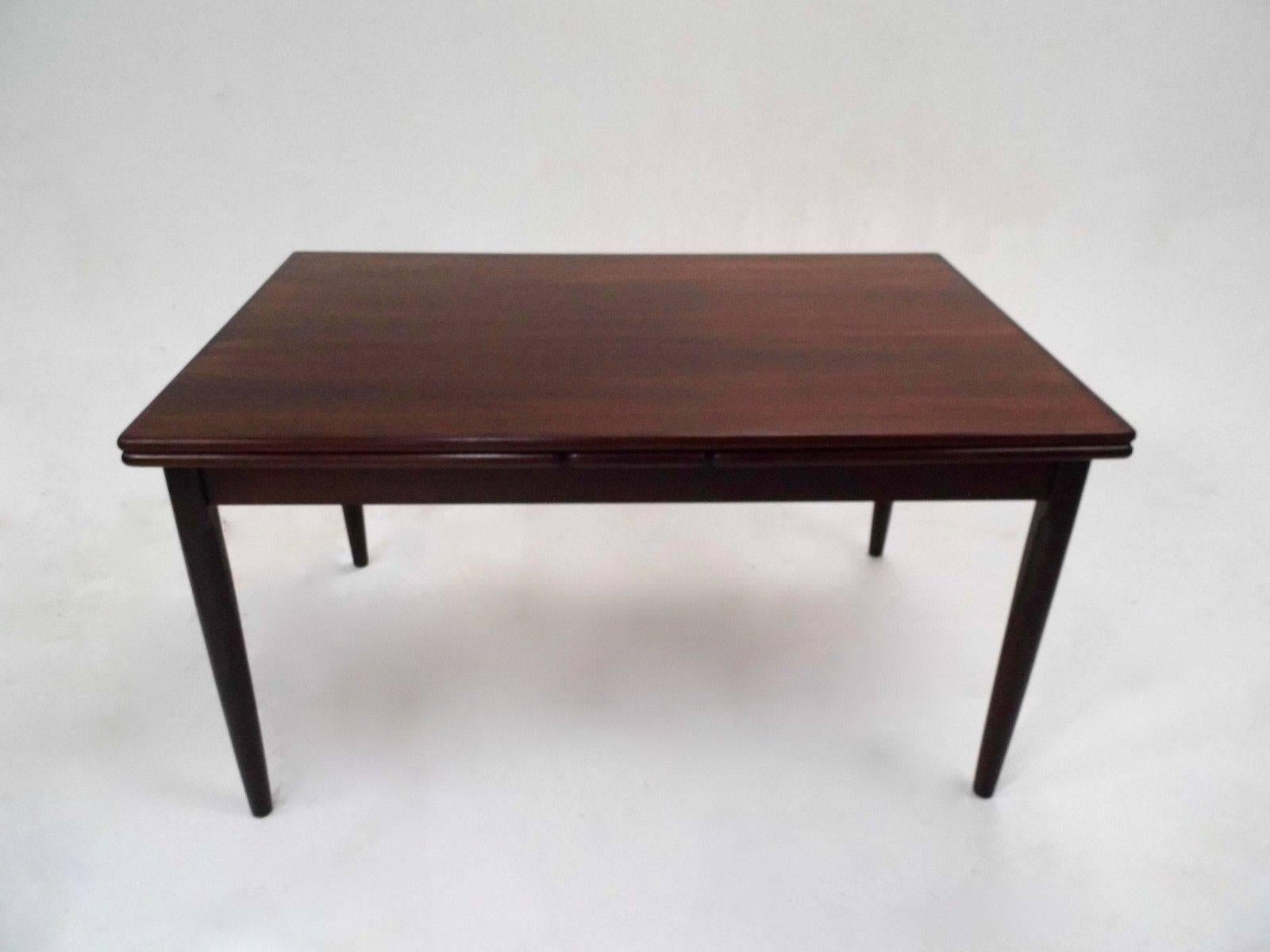 A beautiful Danish large rosewood extending dining table, this would make a stylish addition to any dining area. The table has two extension panels which fit discreetly below the top panel and can be pulled out when needed. A striking piece of
